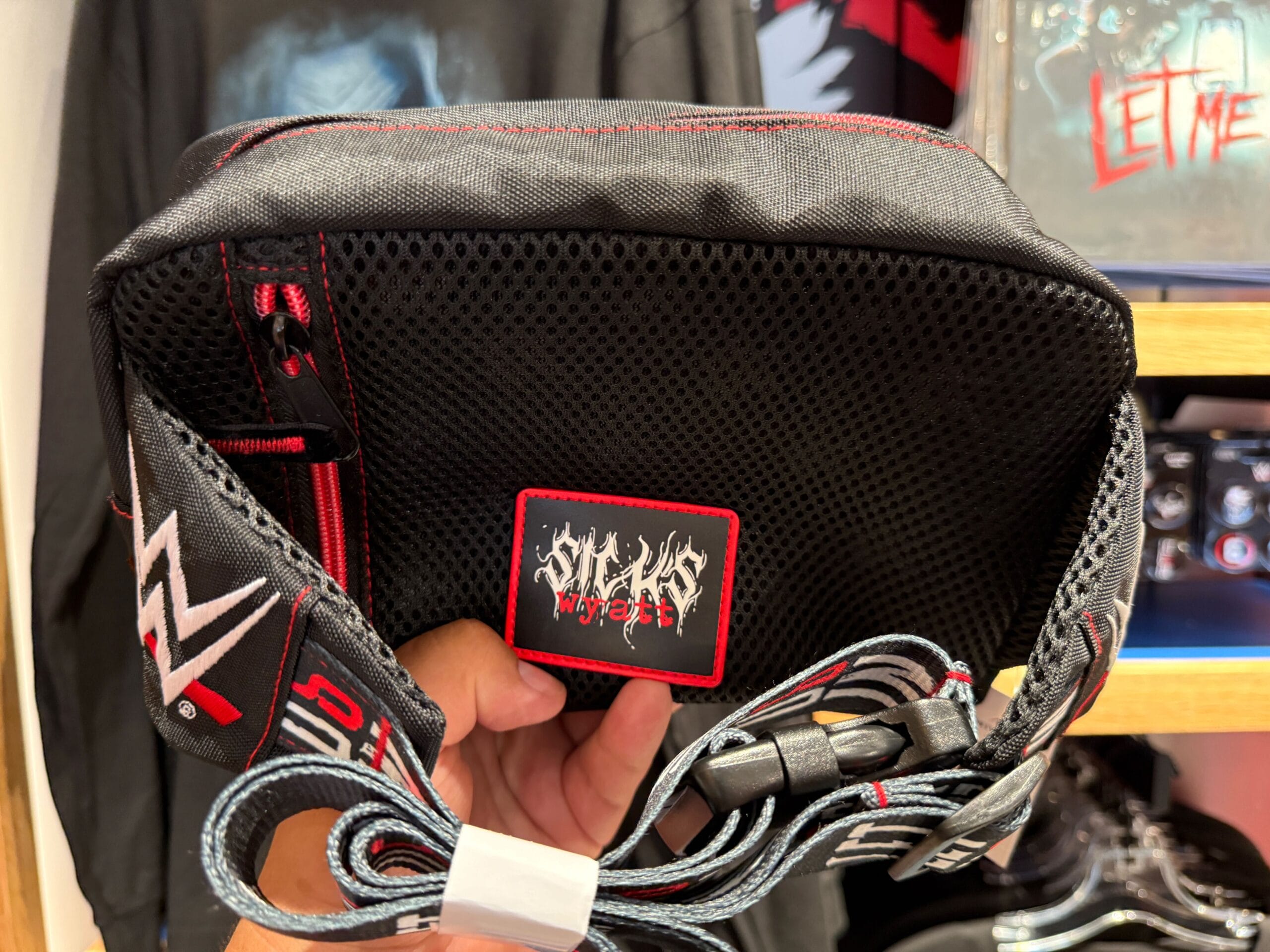 A hand holds a black WWE sling bag with a “Wyatt Sicks” patch, perfect for HHN Merch at Universal Orlando Resort.