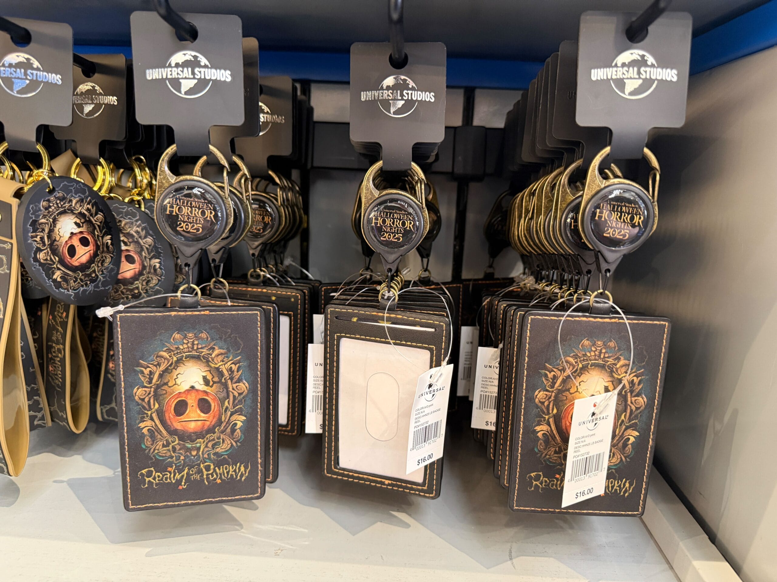 A display of “Realm of the Pumpkin” HHN Merch 2025 card holders and keychains at a souvenir shop.