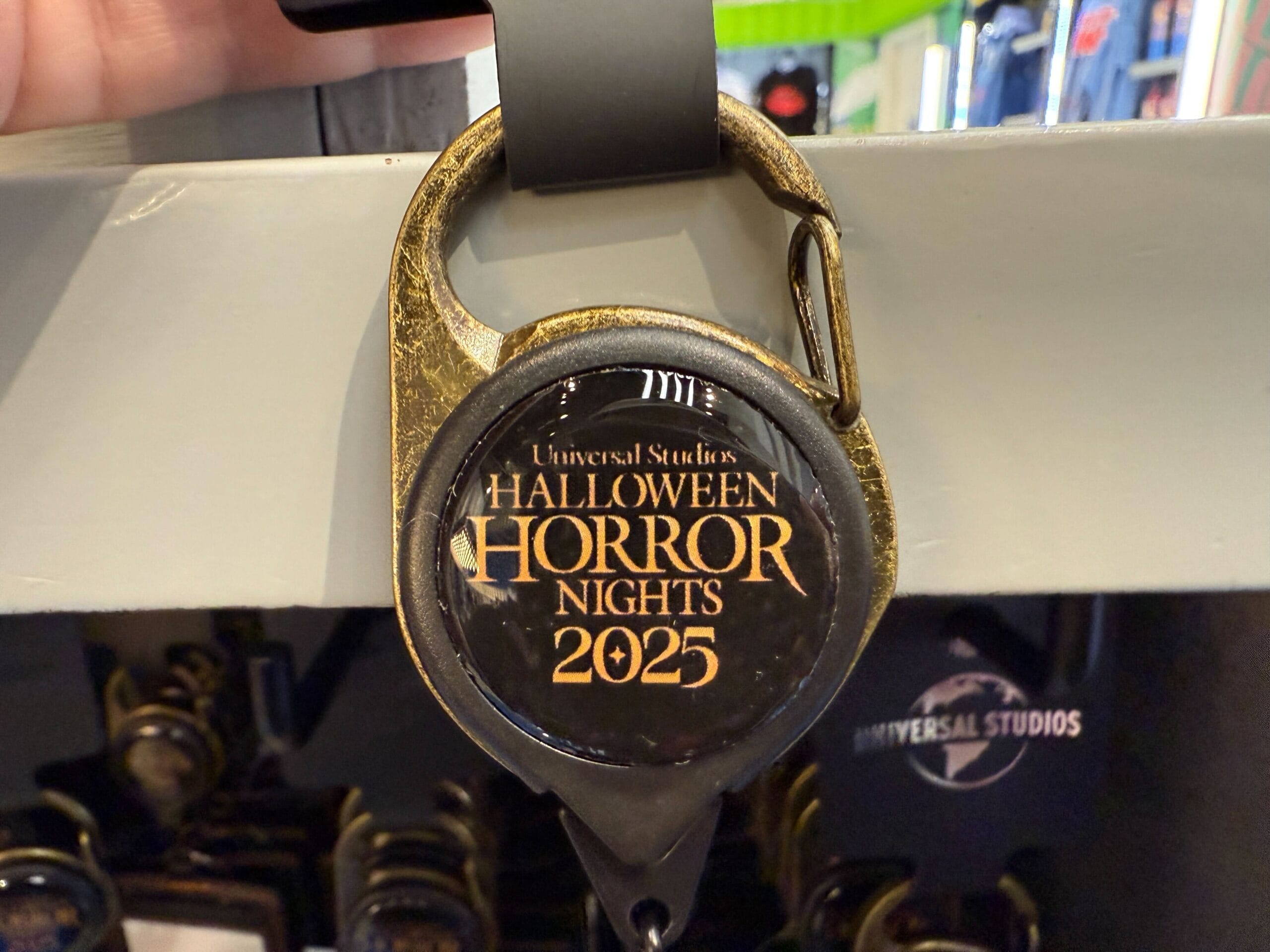 A keychain featuring the "Halloween Horror Nights 2025" logo hangs among exclusive Universal Orlando Resort merch.