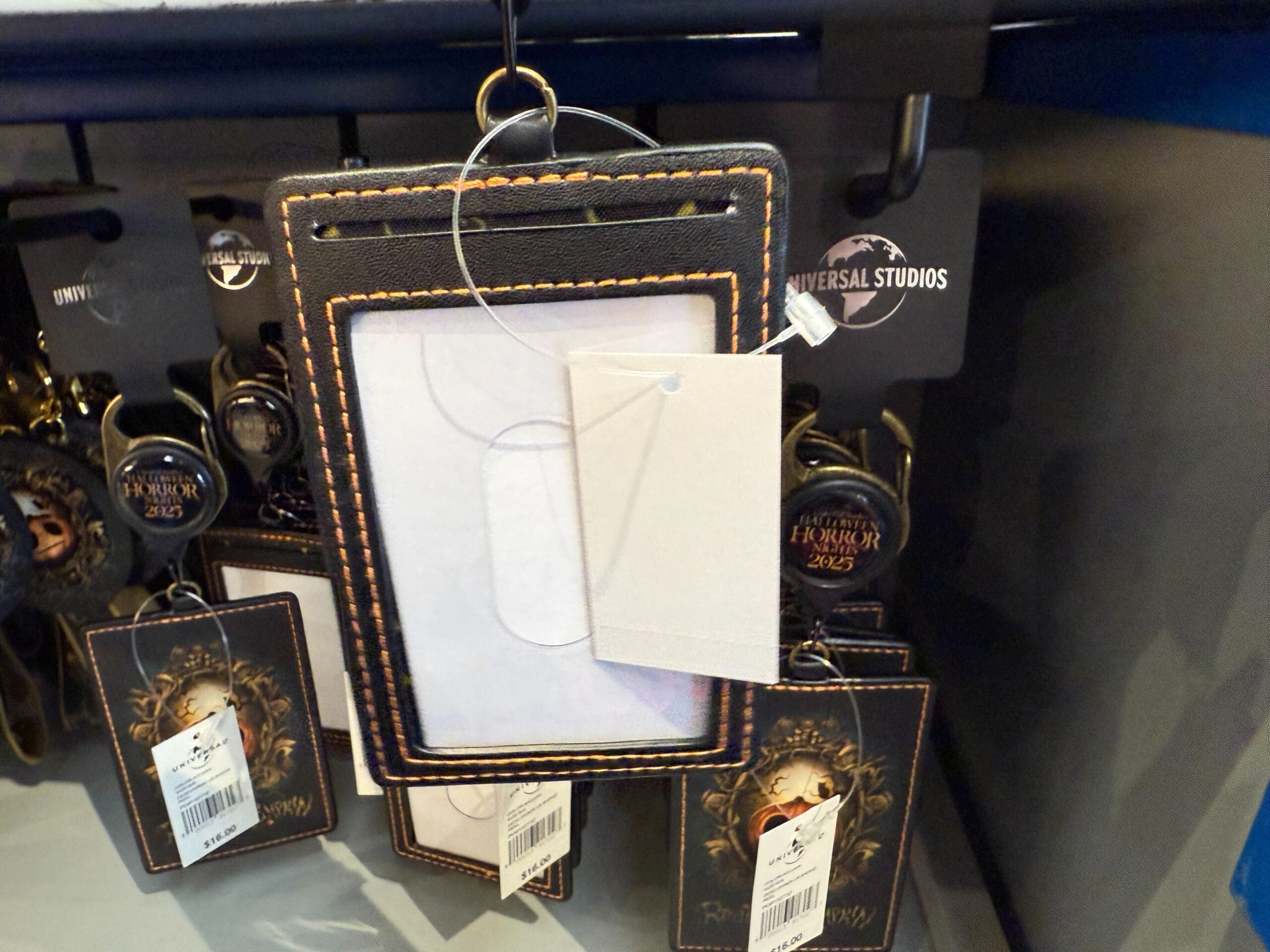Black and brown badge holders are displayed on a rack with Universal Orlando Resort tags visible in the background.