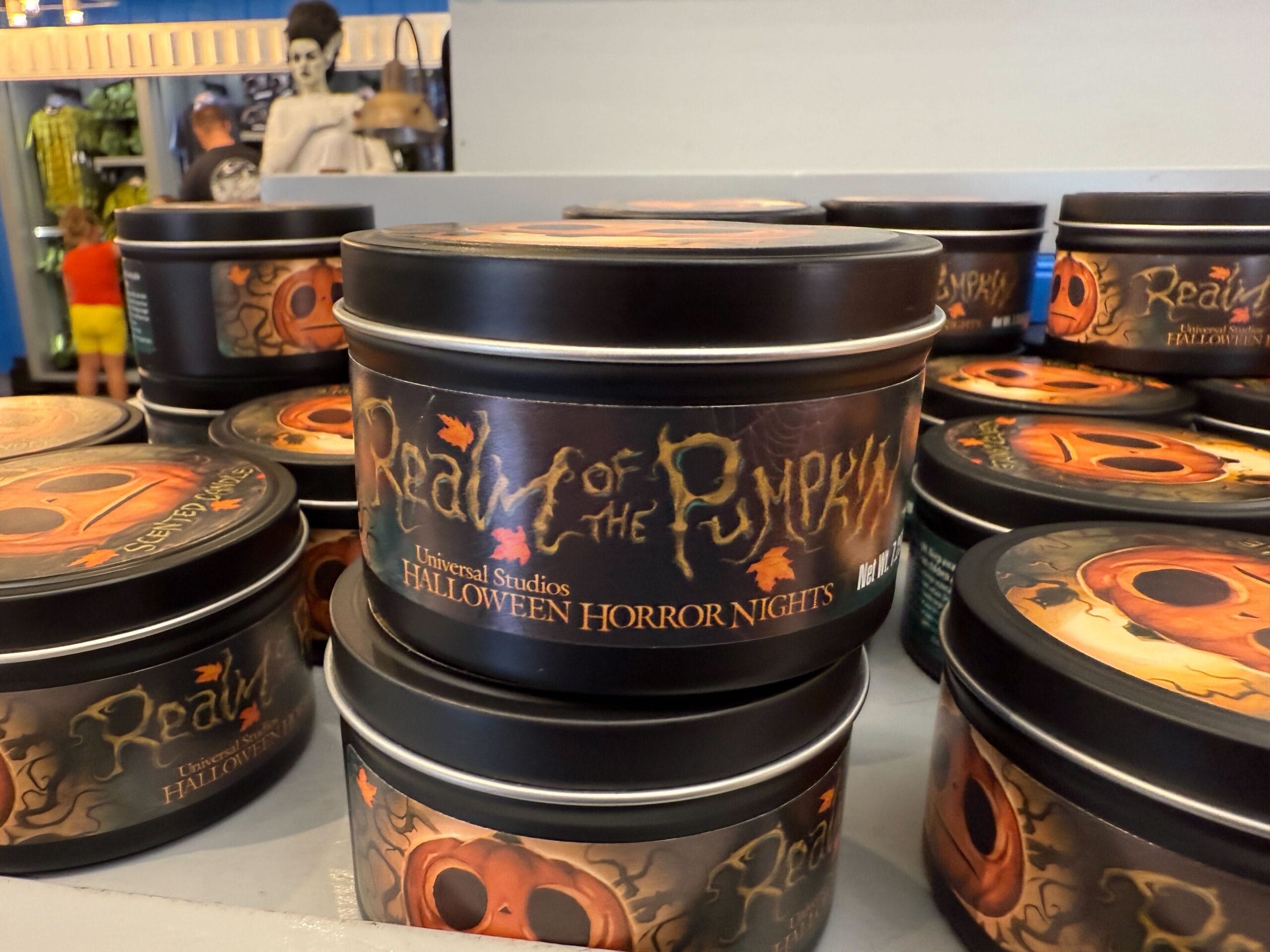 Round tins labeled "Realm of the Pumpkin" featuring Lil Boo Merchandise stacked for Halloween Horror Nights at Universal Studios.