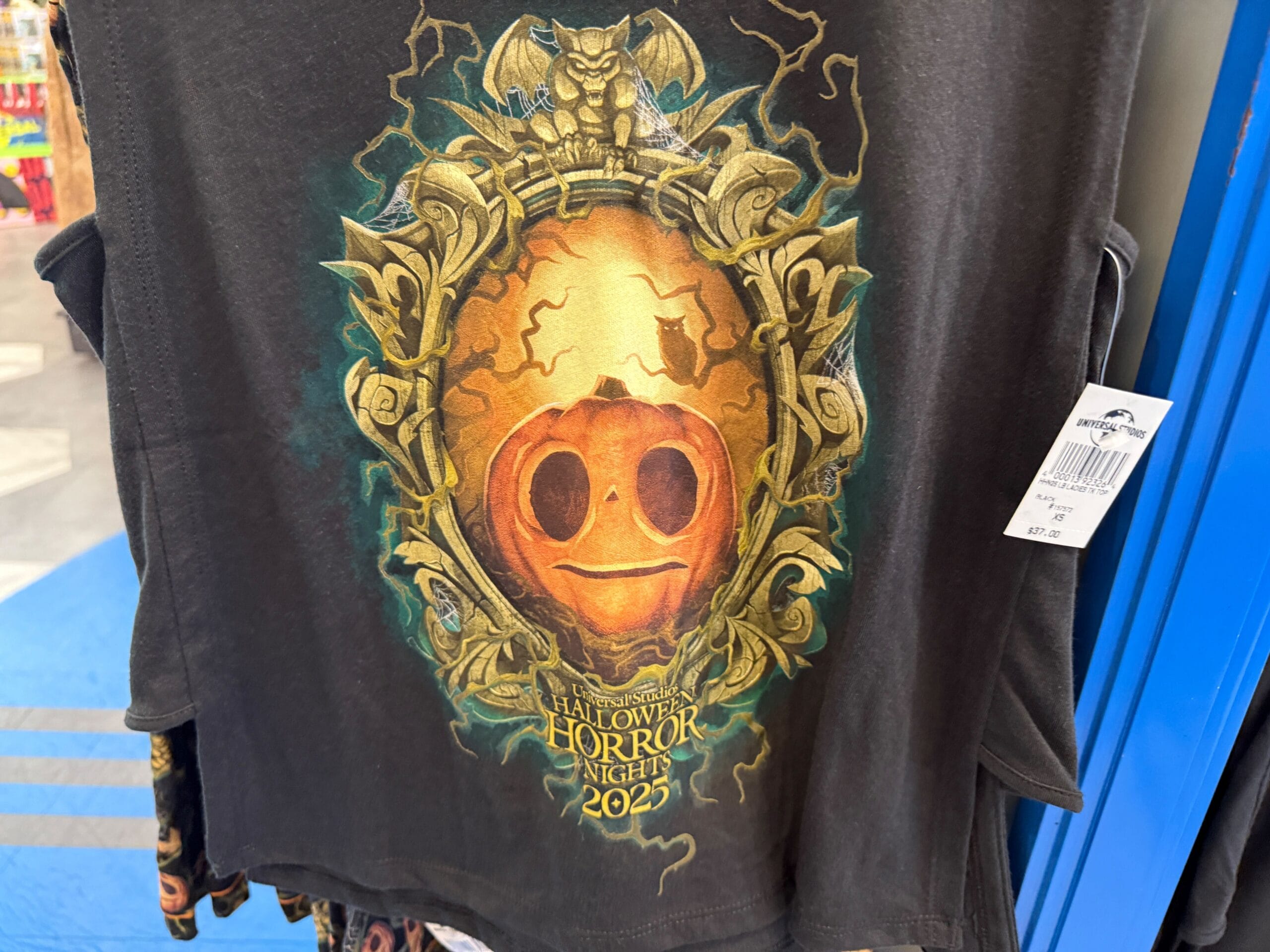 Black shirt featuring Lil Boo with a golden frame around a pumpkin face and "Halloween Horror Nights 2023" at the bottom.