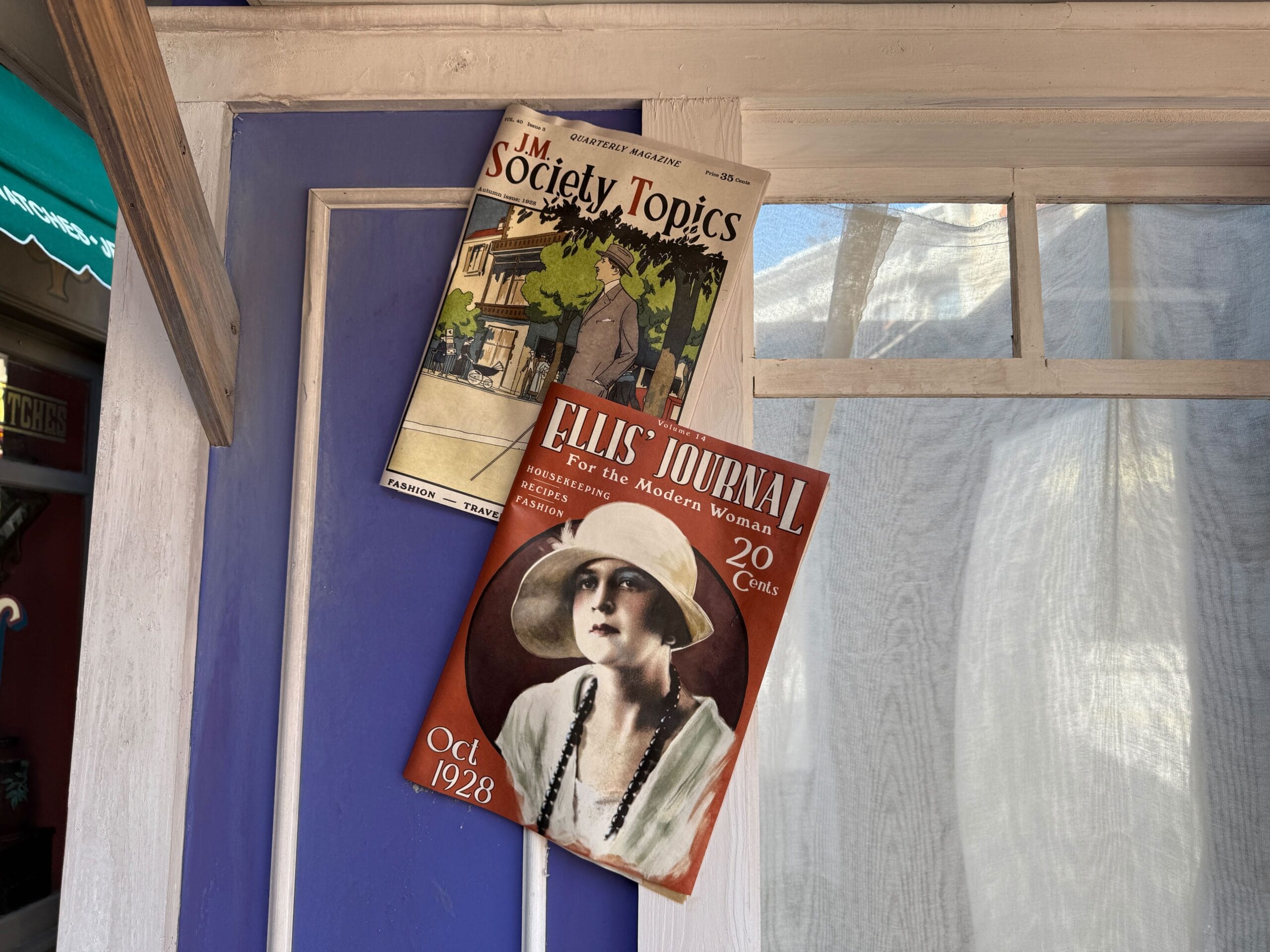 Two vintage magazines, one titled "JM Society Topics" and the other "Ellis' Journal," are pinned to a purple wall.