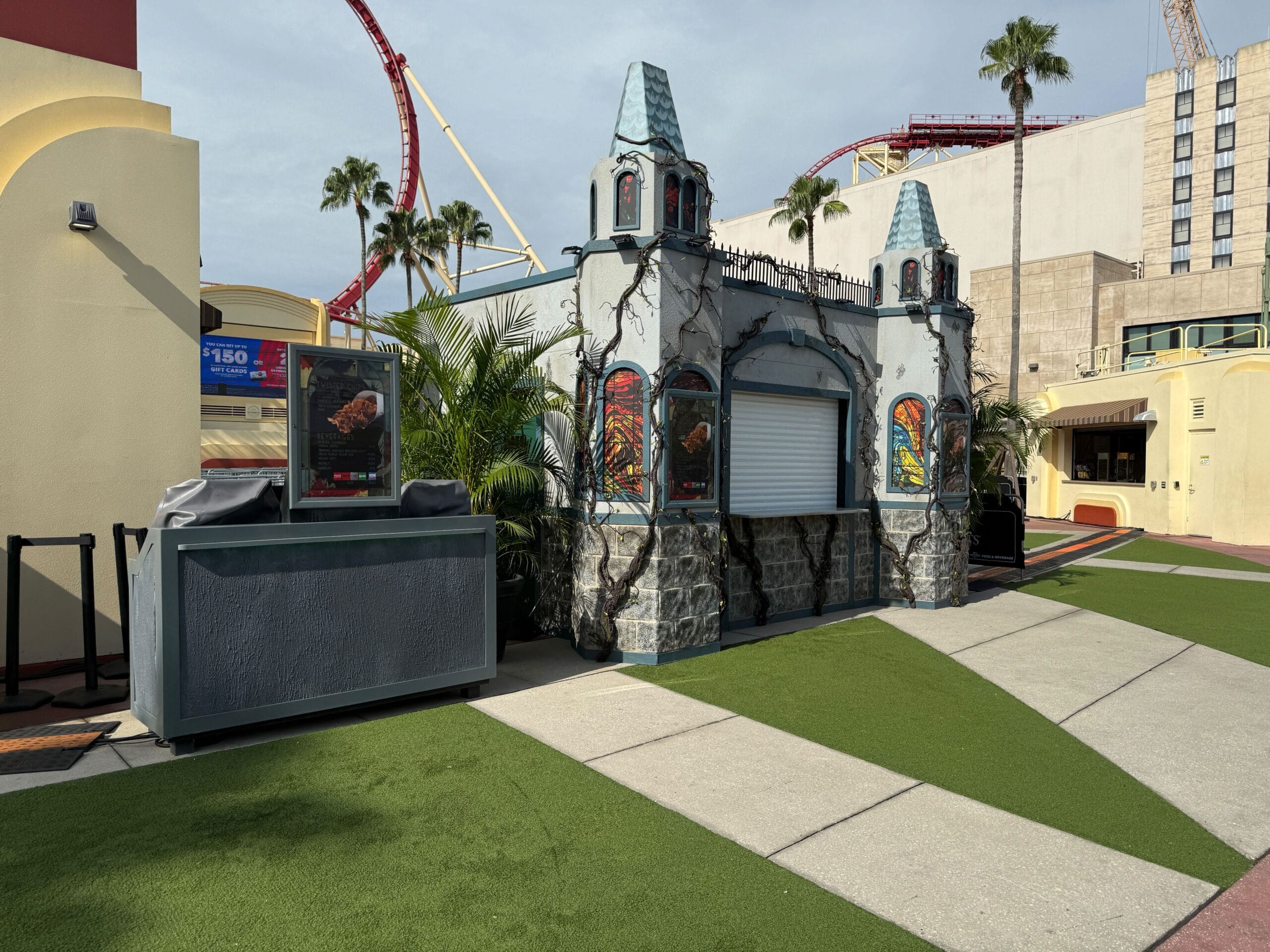 A closed Gothic-style concession stand at Universal Studios Florida, set near palm trees and a coaster for Halloween Horror Nights 2025.