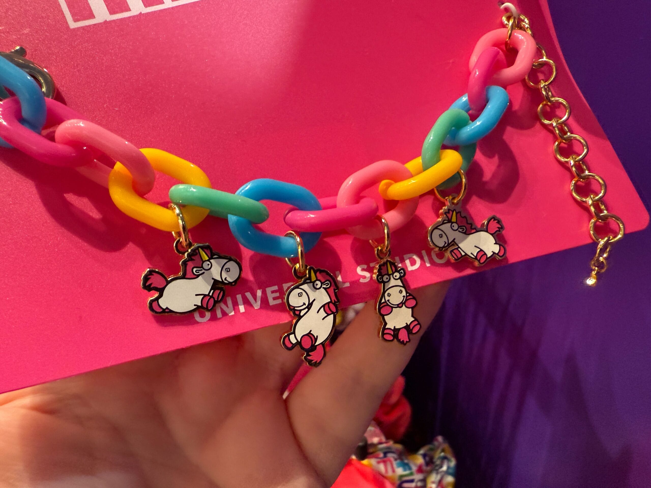 A colorful chain bracelet with four Fluffy Unicorn charms, displayed on a pink Universal Orlando Resort card.