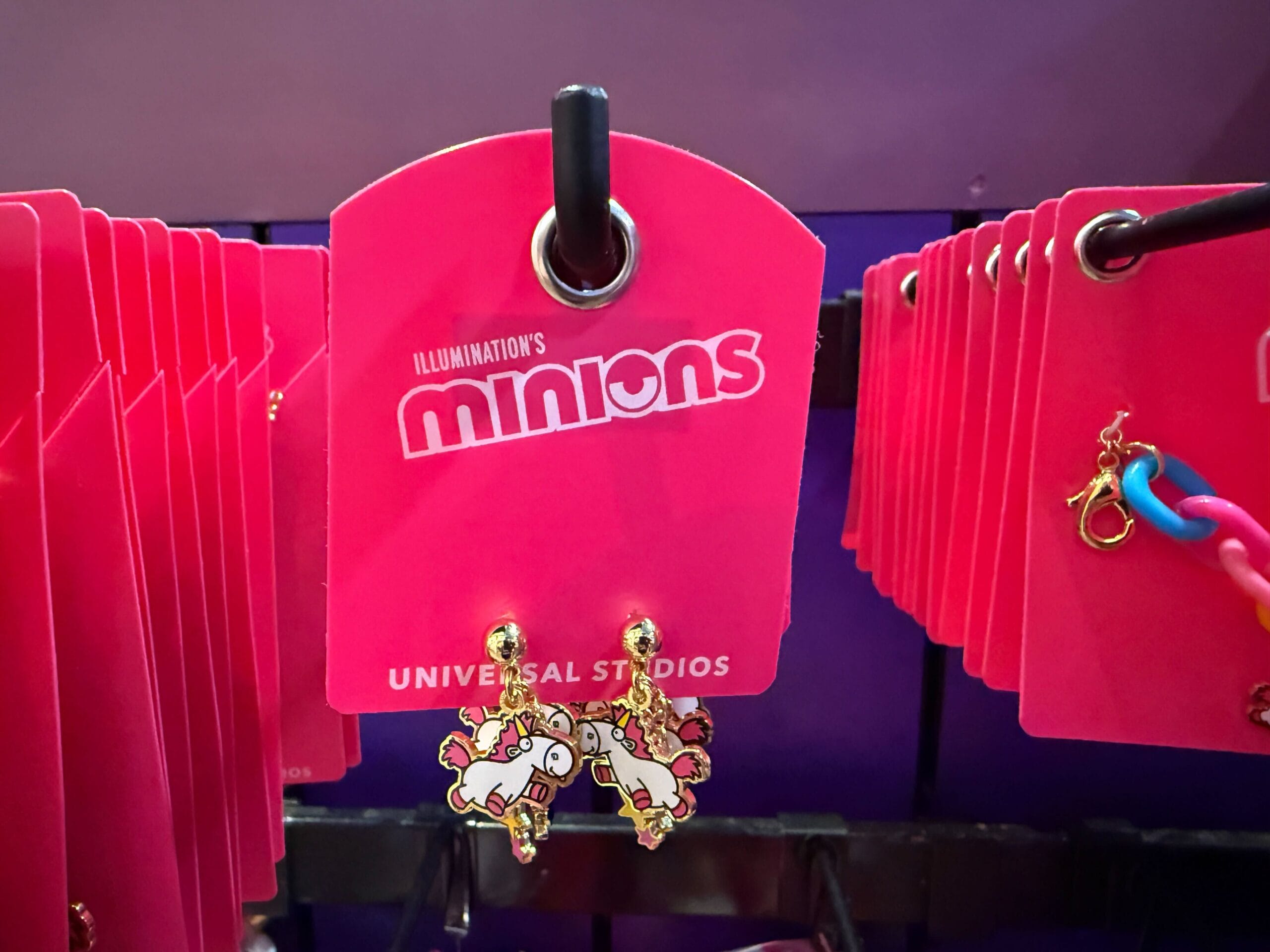 A pink Minions display card holds Fluffy Unicorn earrings at a Universal Orlando Resort store.