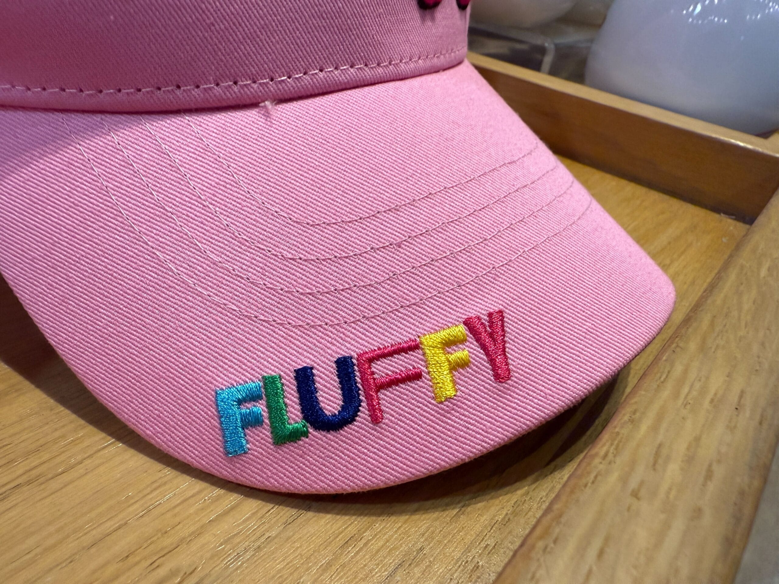 A pink cap with "FLUFFY" in rainbow letters, inspired by the Fluffy Unicorn from Universal Orlando Resort.
