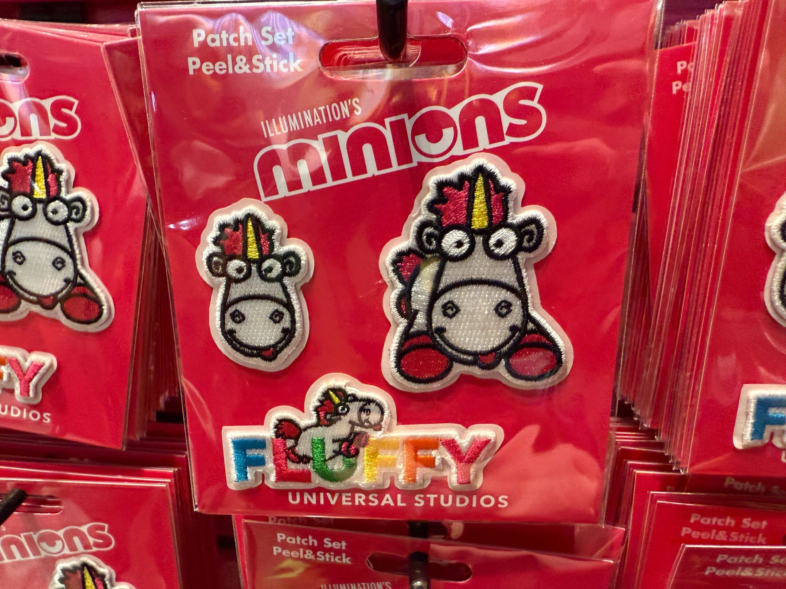 Two peel-and-stick Fluffy Unicorn patches from Minions, with “Fluffy” text and Universal Orlando Resort branding.