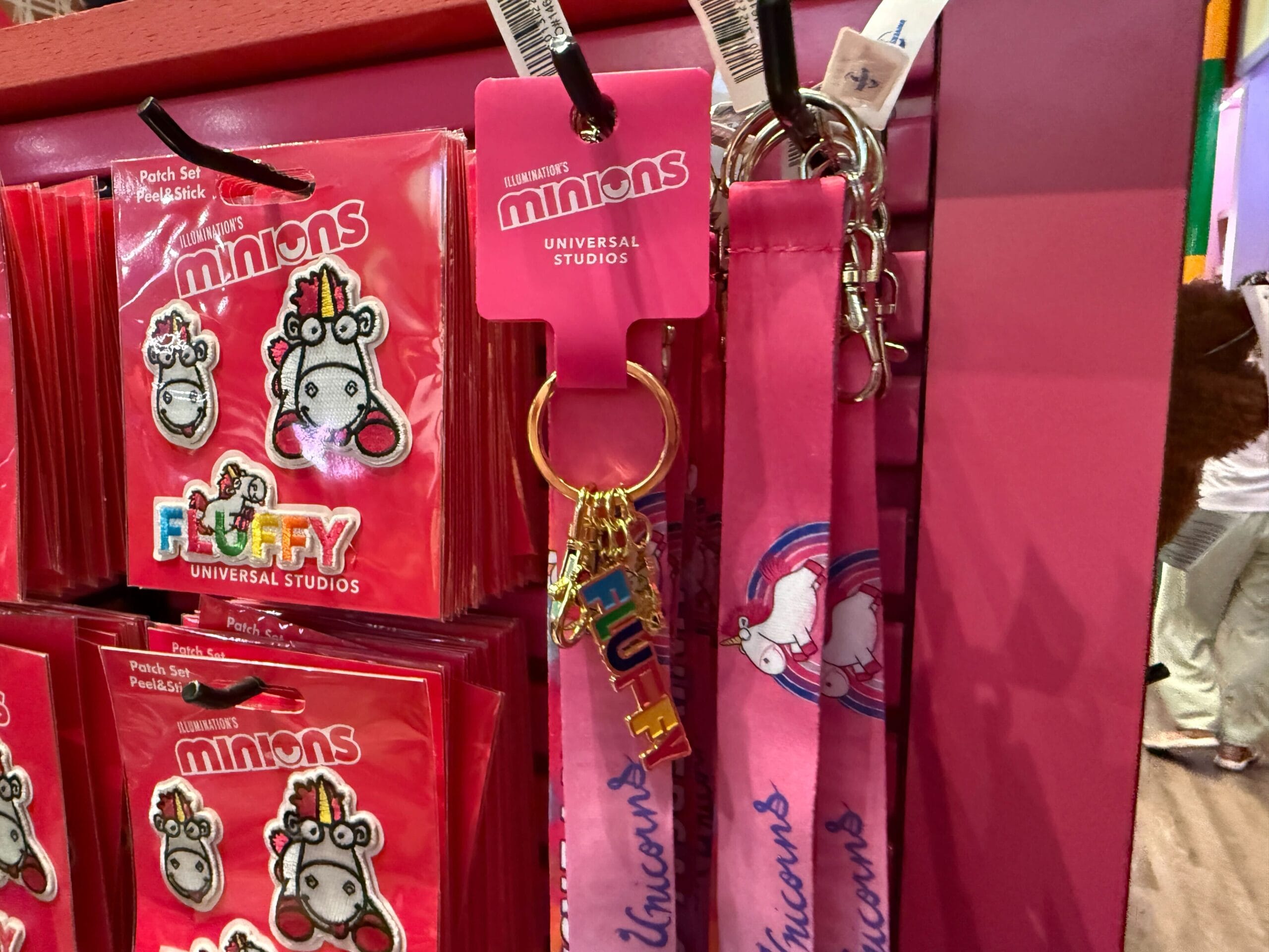 Fluffy Unicorn keychains and lanyards from Minions on a pink shelf at Universal Orlando Resort.