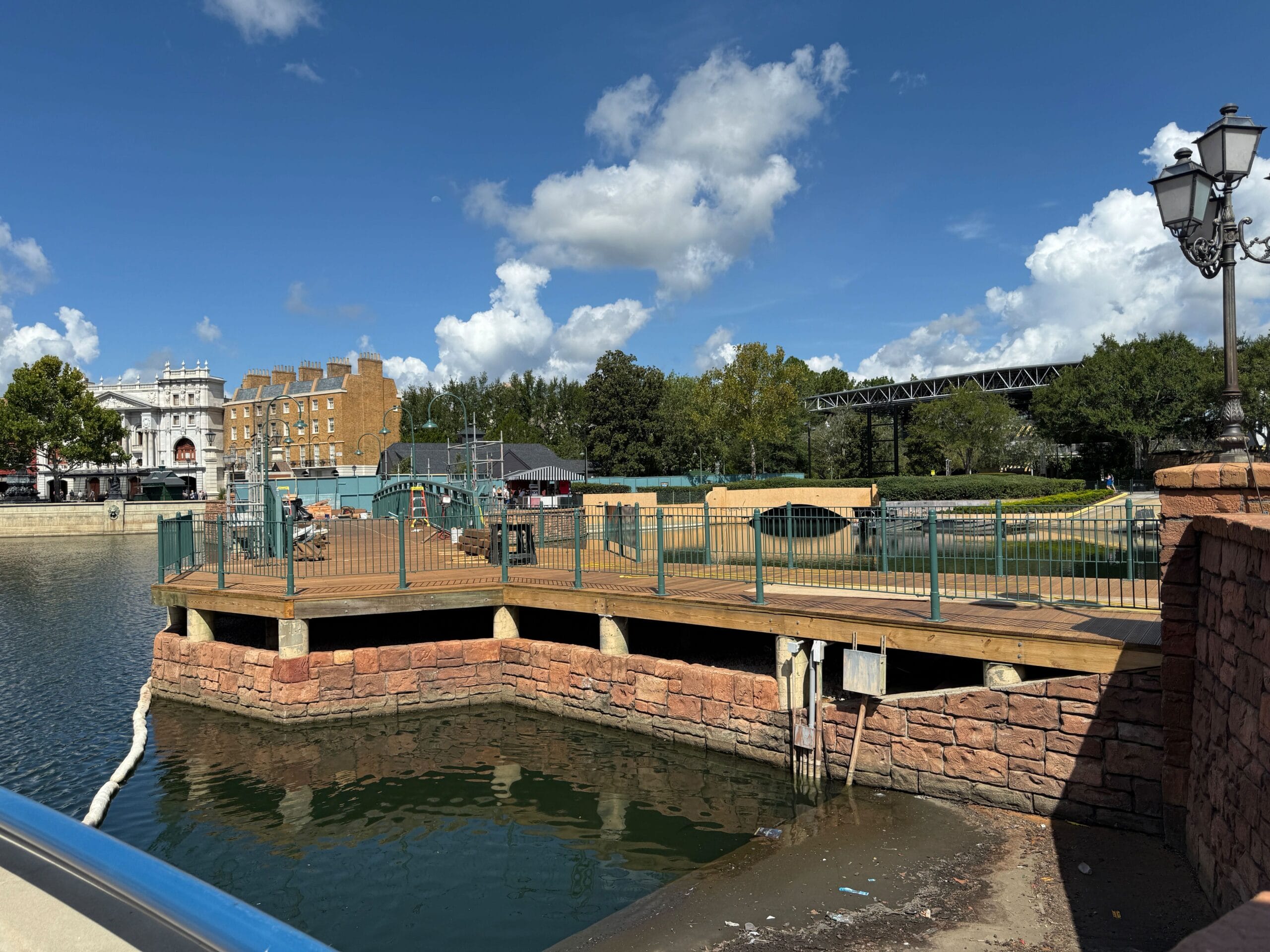 A wooden platform with green fencing by the water, possibly part of construction projects at Universal Studios Florida.