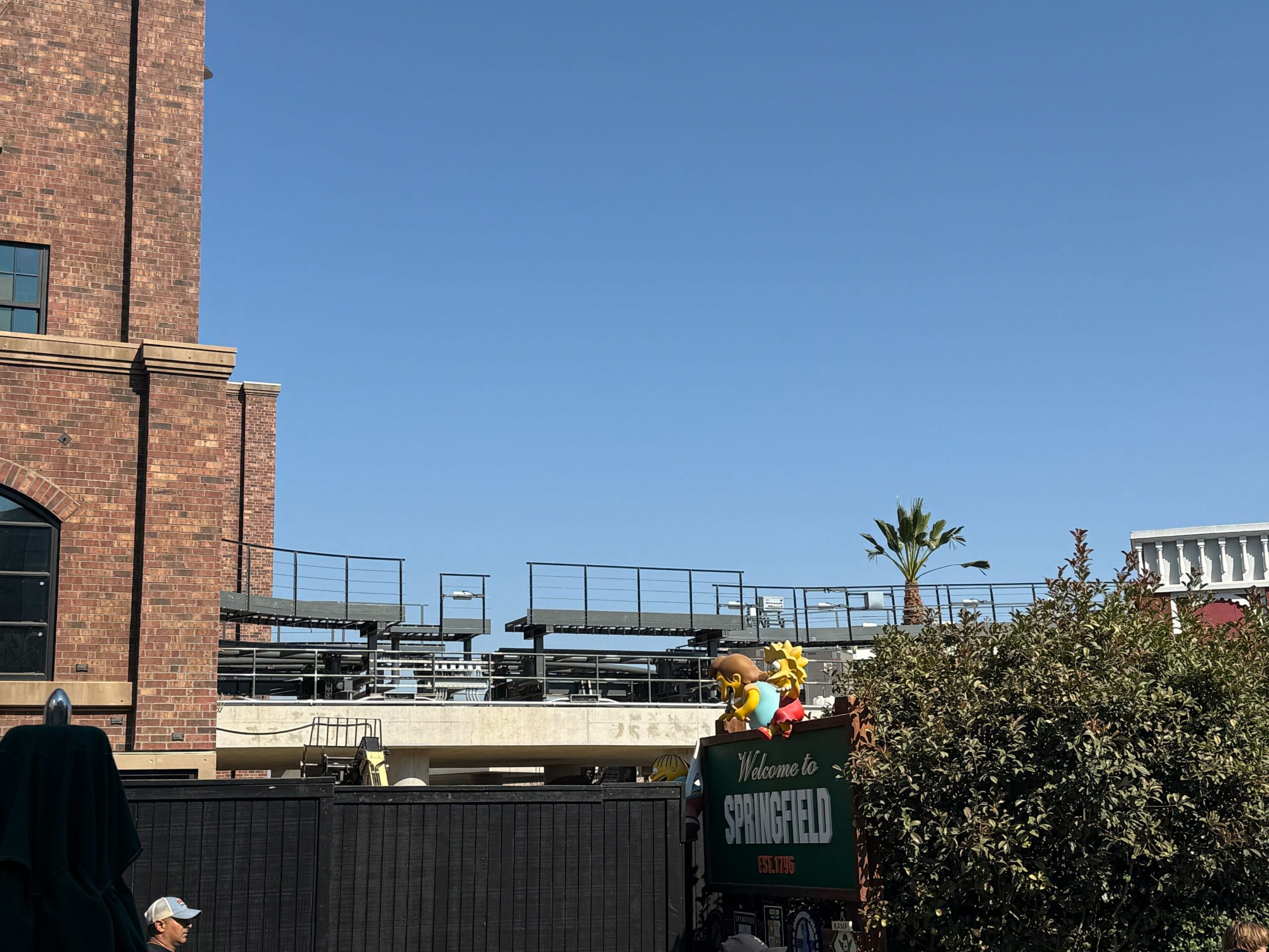 A "Welcome to Springfield" sign with cartoon figures in front of a brick building and blue sky in the background.