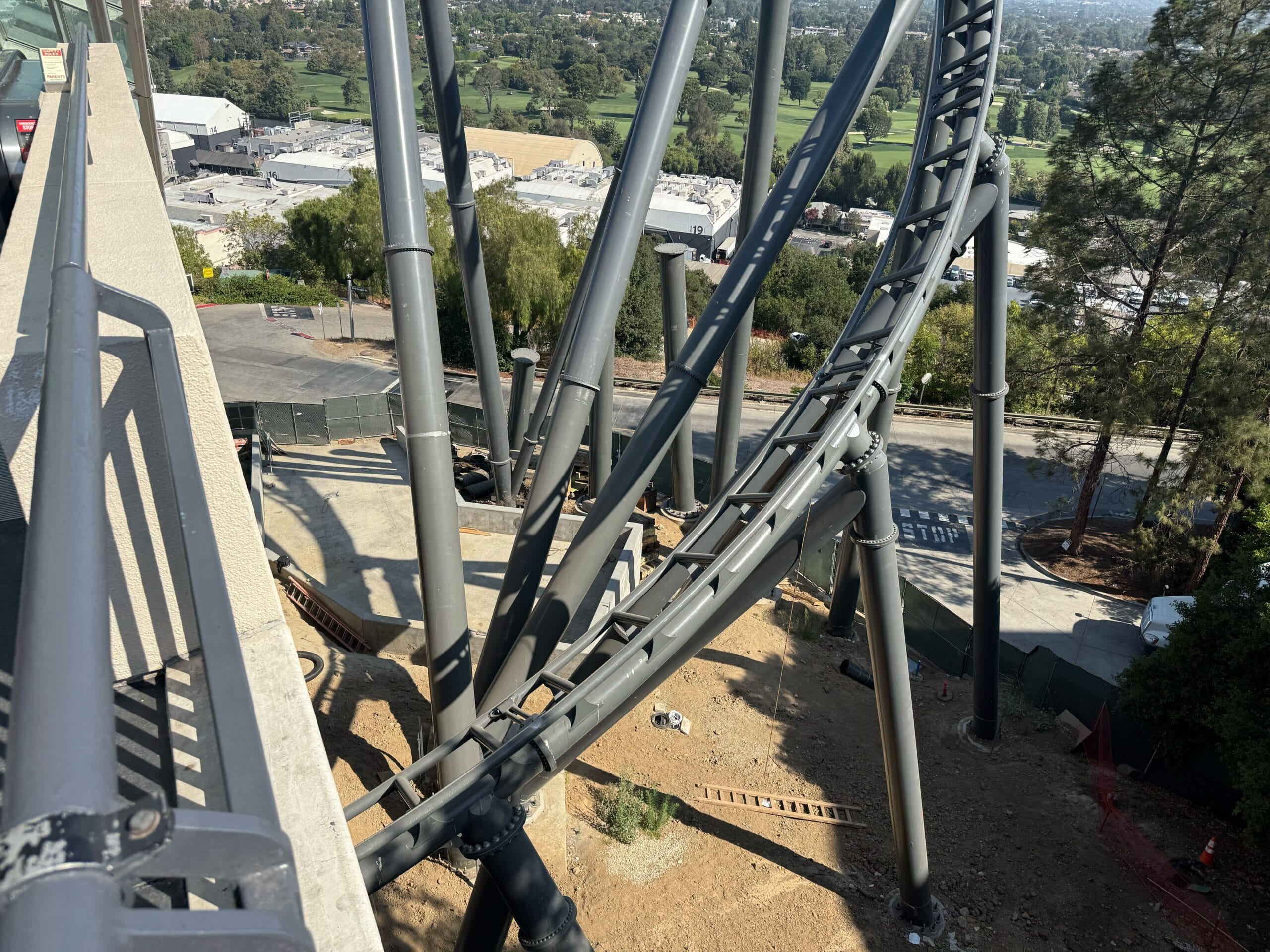View from a platform overlooking Universal Studios Hollywood’s roller coaster track, with supports and trees in the background.