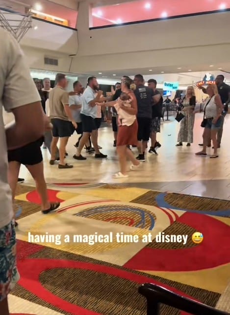 Disney Contemporary Resort Fight - A group violently argues indoors at Disney's Contemporary Resort, with a woman holding a child near the center.