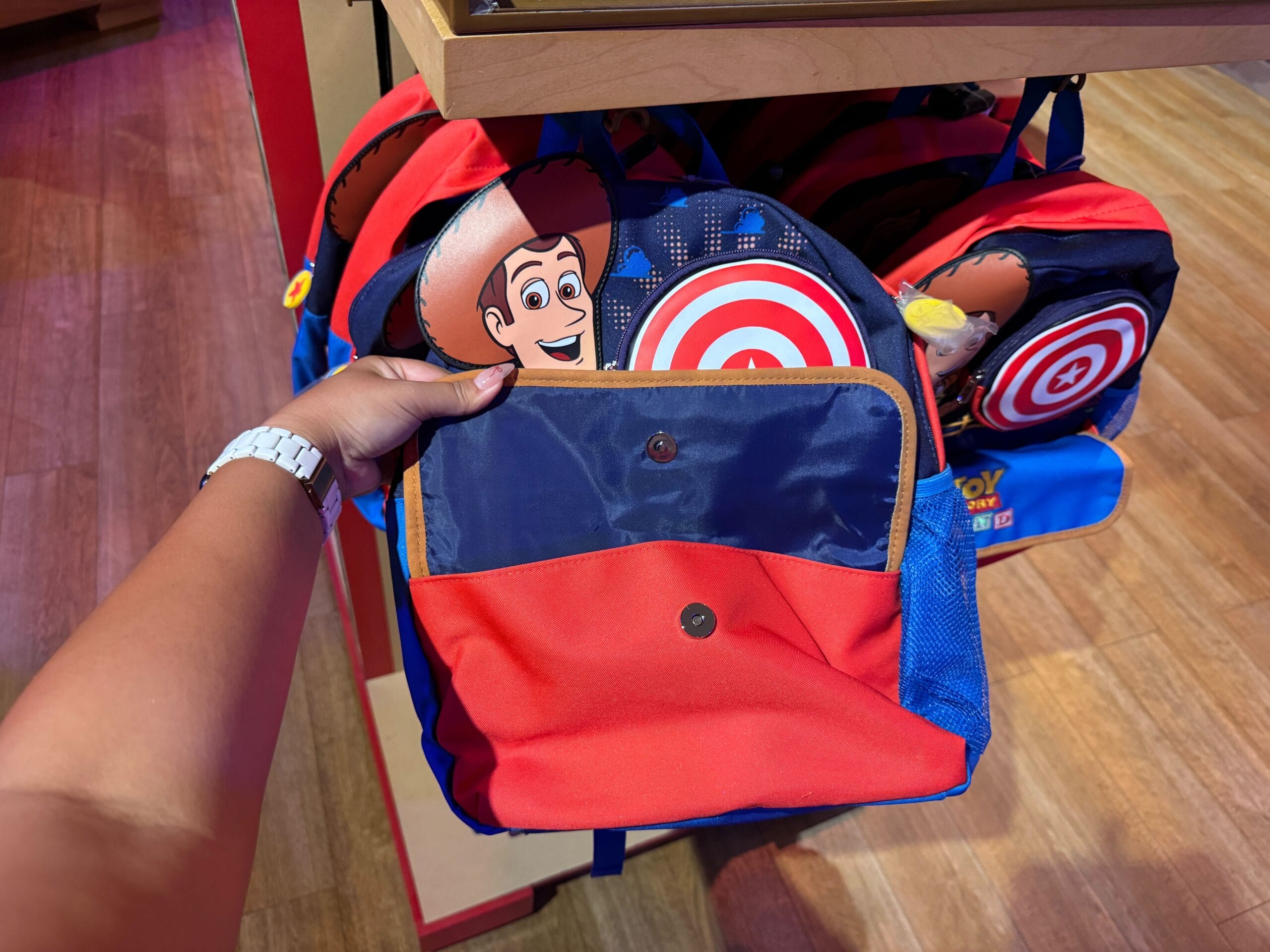 A person holds a red and blue Toy Story backpack with Woody’s face and target designs in a store.
