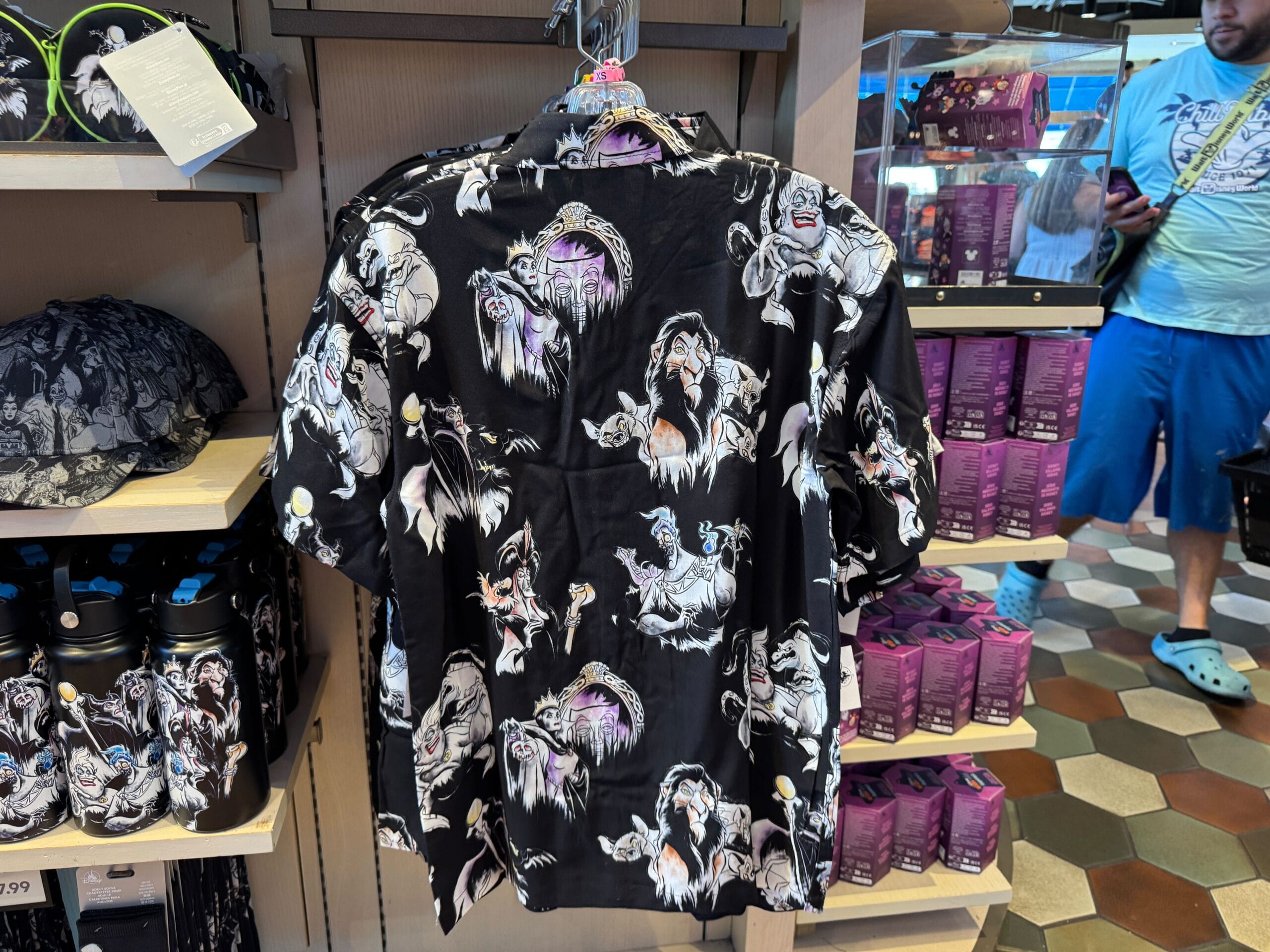 Black button-up shirt with Disney villain characters printed, displayed on a hanger in a store.