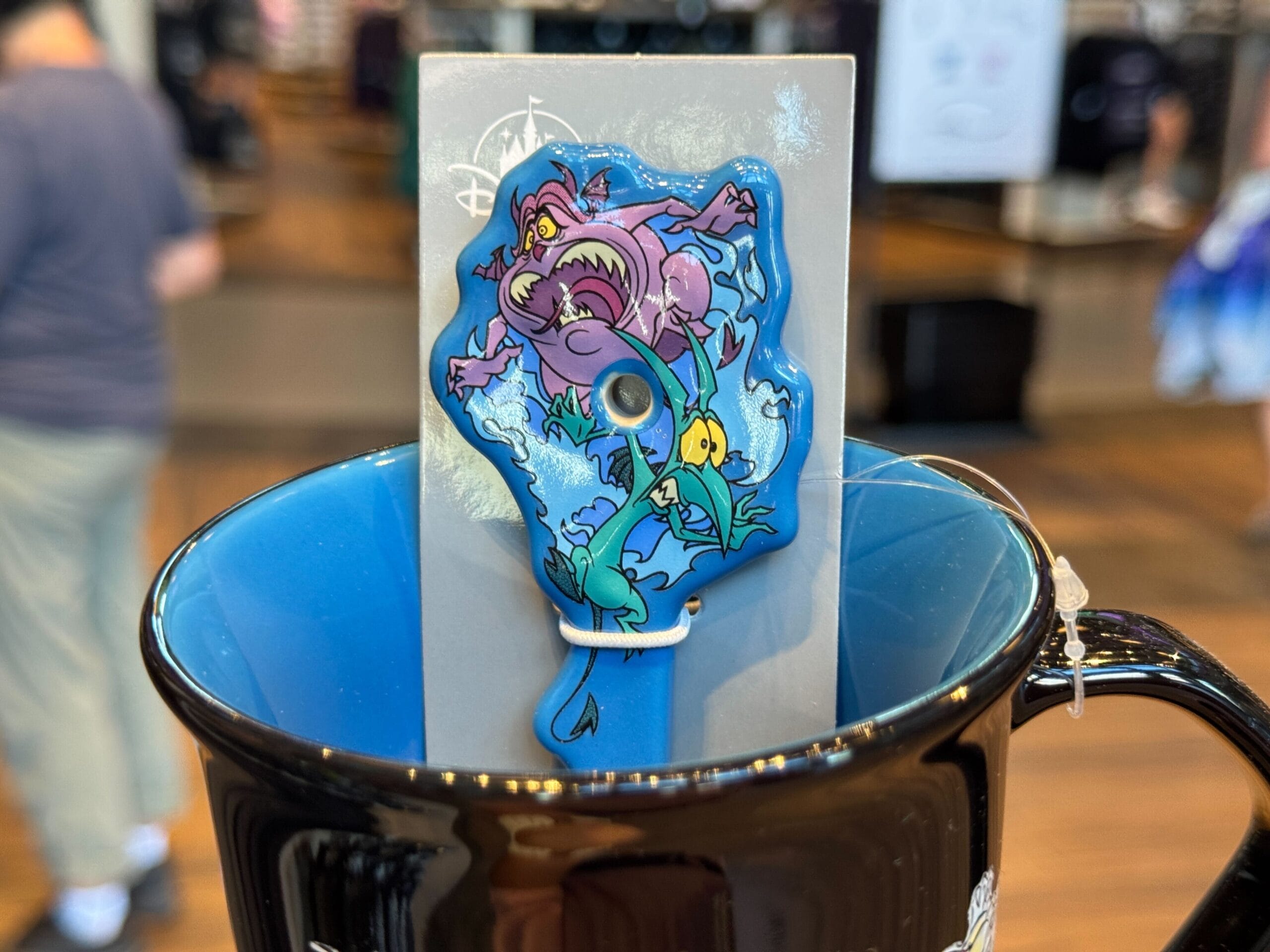 Colorful Disney Villains merchandise pin with Ursula, Ariel, and Flounder in a mug—perfect for Halloween 2025 collectors!