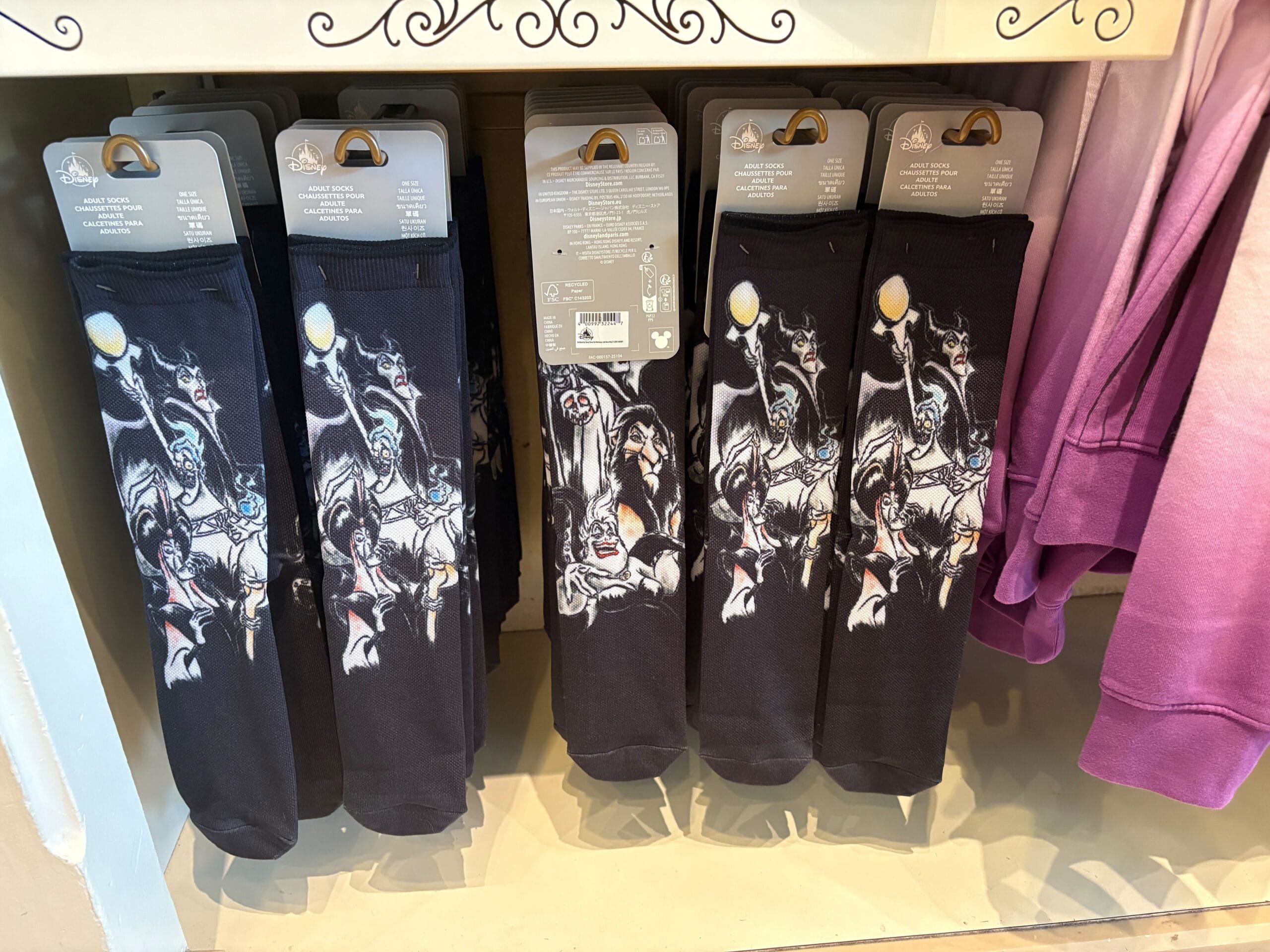 Black socks featuring Disney Villains merchandise displayed on a store shelf next to pink clothing.