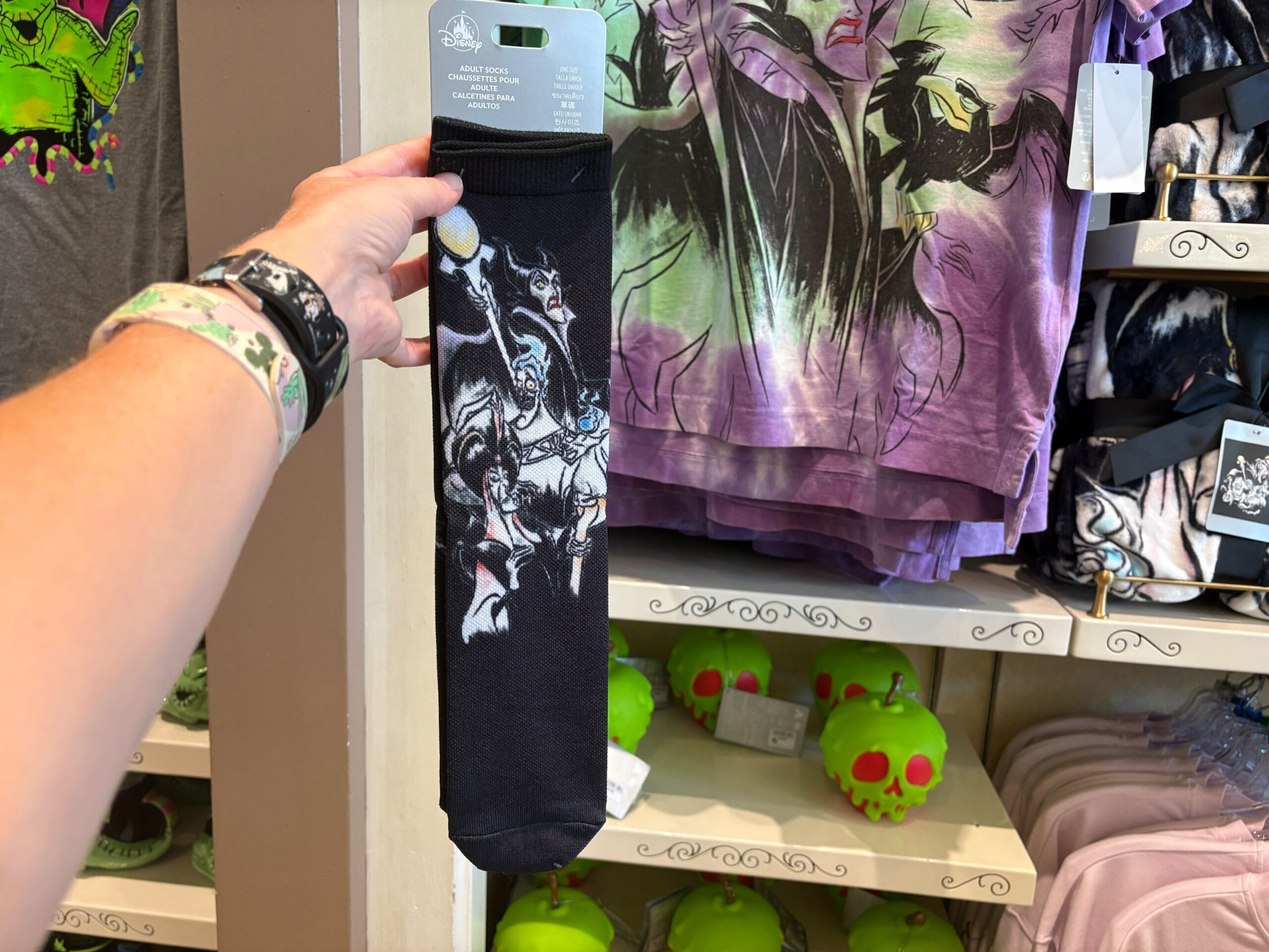 A hand holds up black socks with Maleficent’s dragon design in a Disney Villains merchandise store at Walt Disney World.