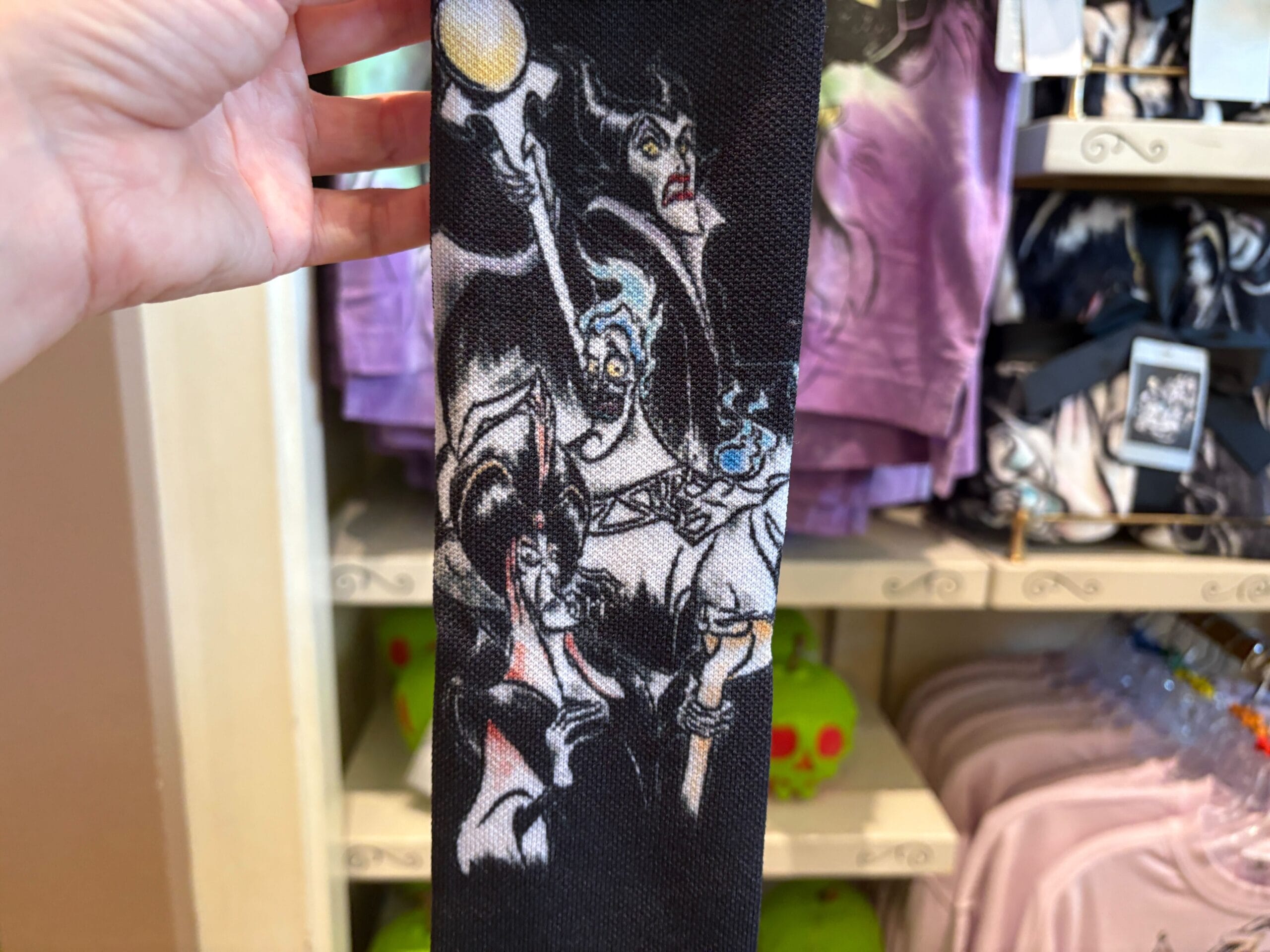 Hand holding fabric featuring Disney villains at a store—perfect Disney Villains merchandise for Halloween 2025.