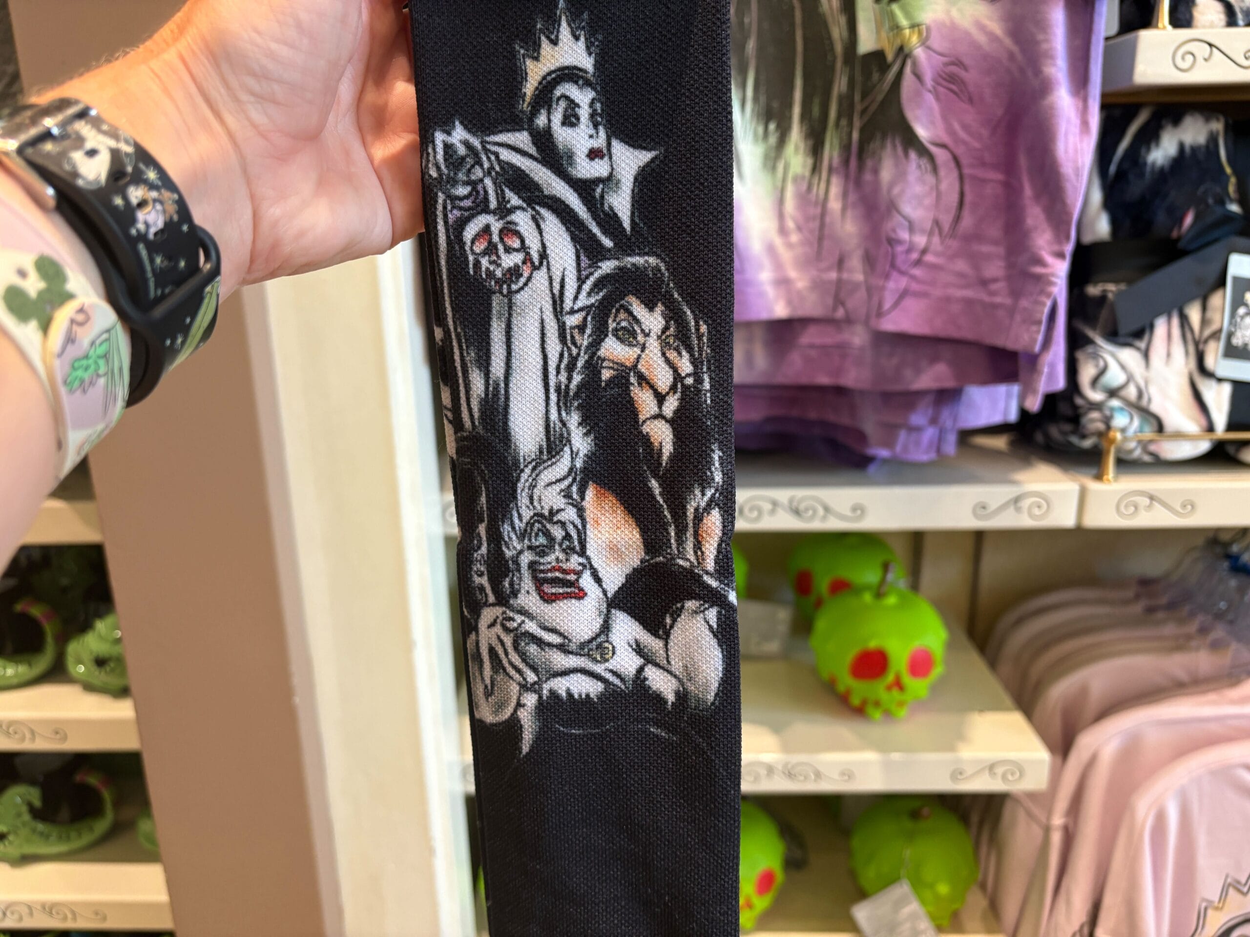 Person holds Disney Villains Merchandise with Evil Queen, Scar, Ursula & Hades at Walt Disney World among green apple souvenirs.
