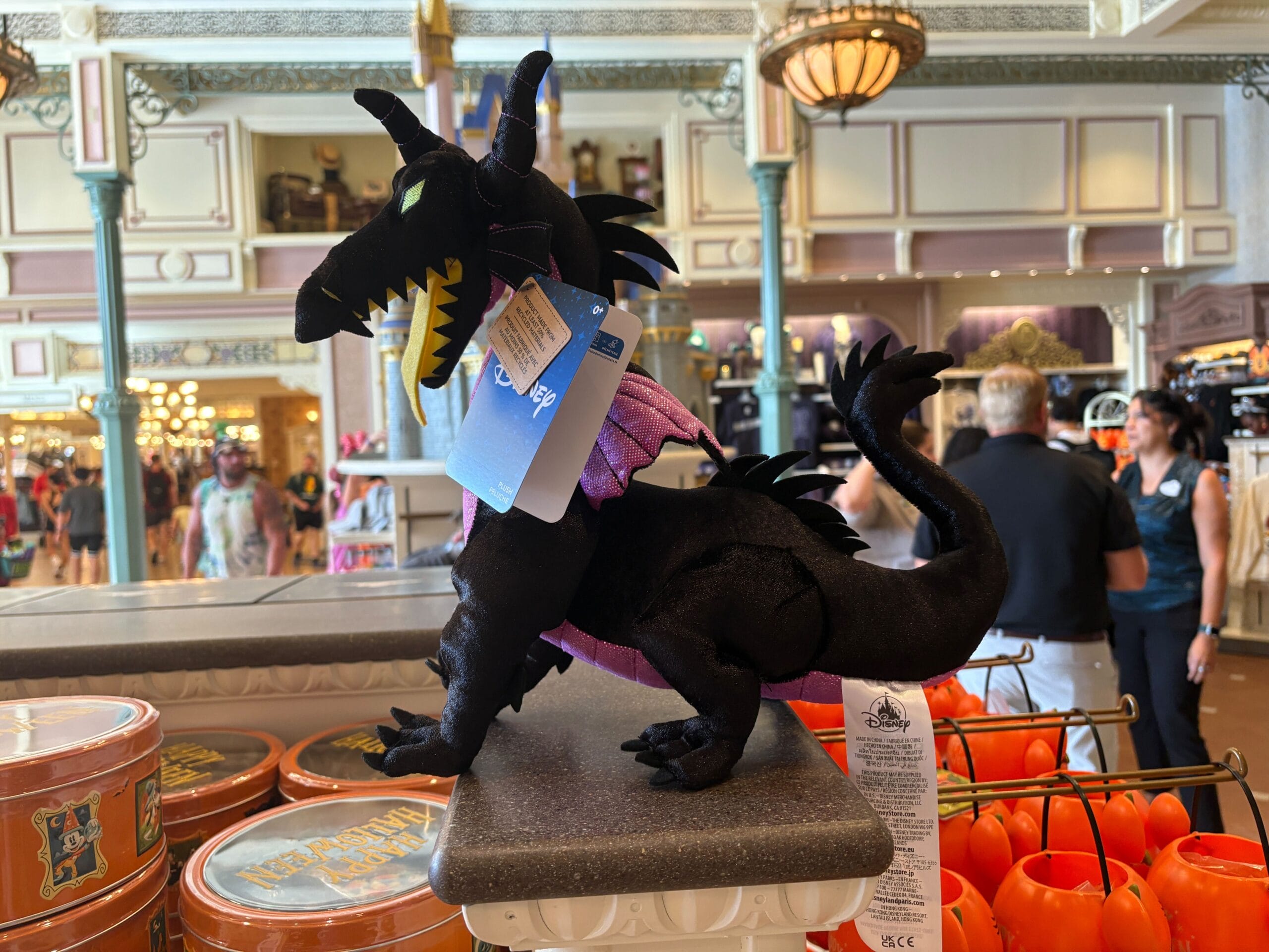 A plush black dragon toy with purple wings, part of Disney Villains merchandise, is on display among Halloween 2025 décor.