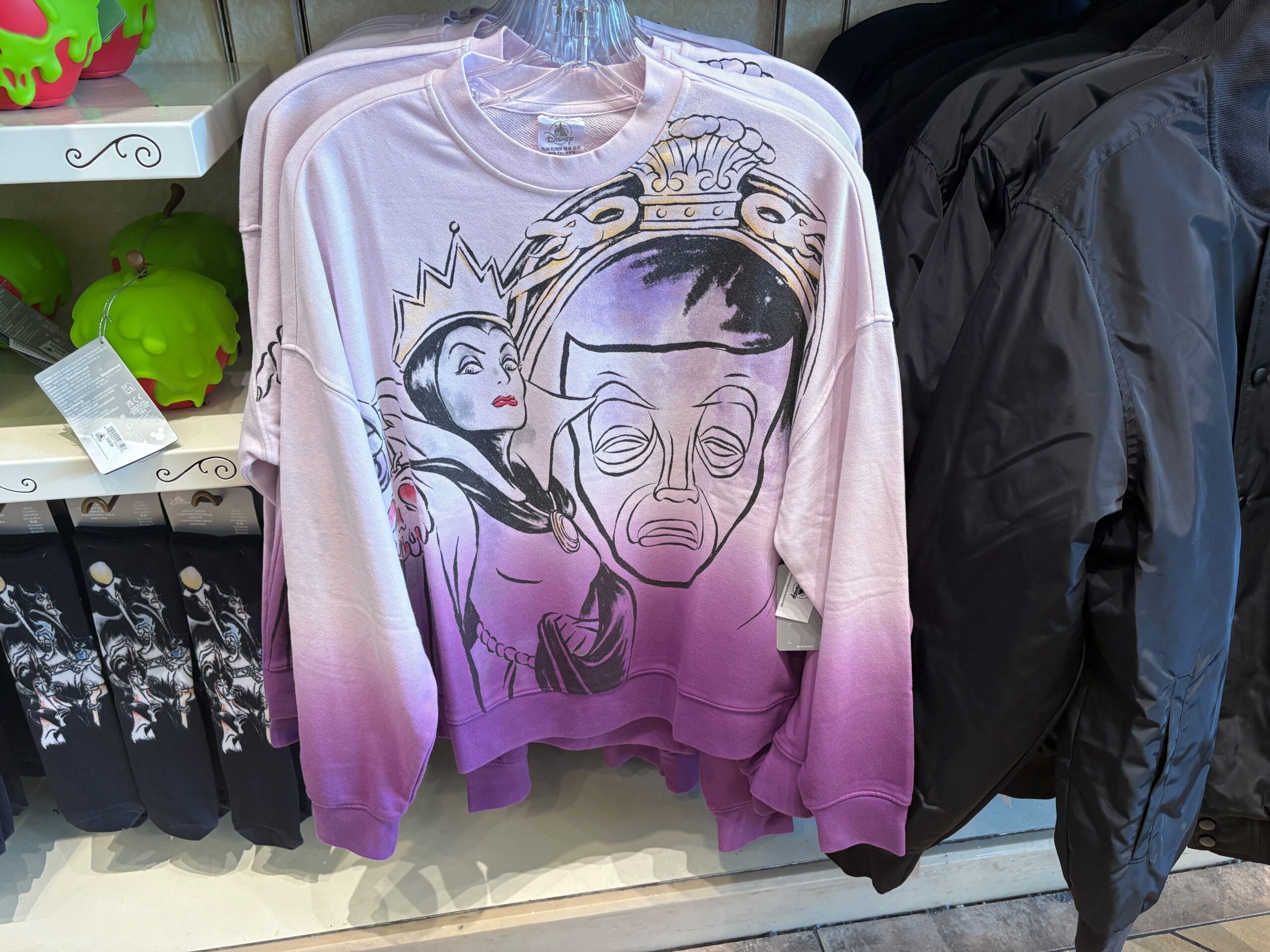 Purple and pink sweatshirt featuring the Evil Queen and the Magic Mirror from Disney’s Snow White hanging on a rack.