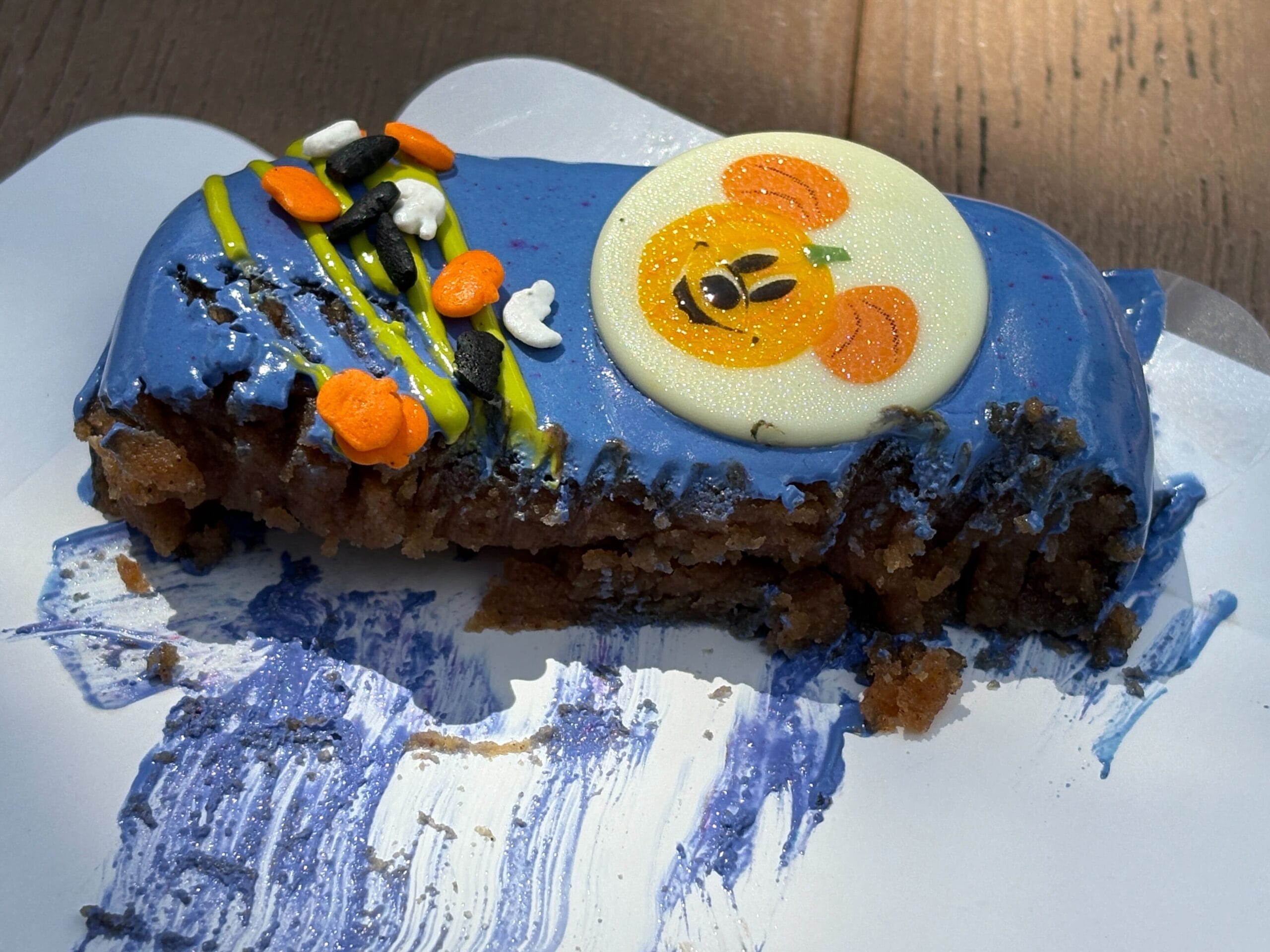 Partially eaten blue-frosted dessert at Disney Springs, with Halloween decorations and a white candy pumpkin face.