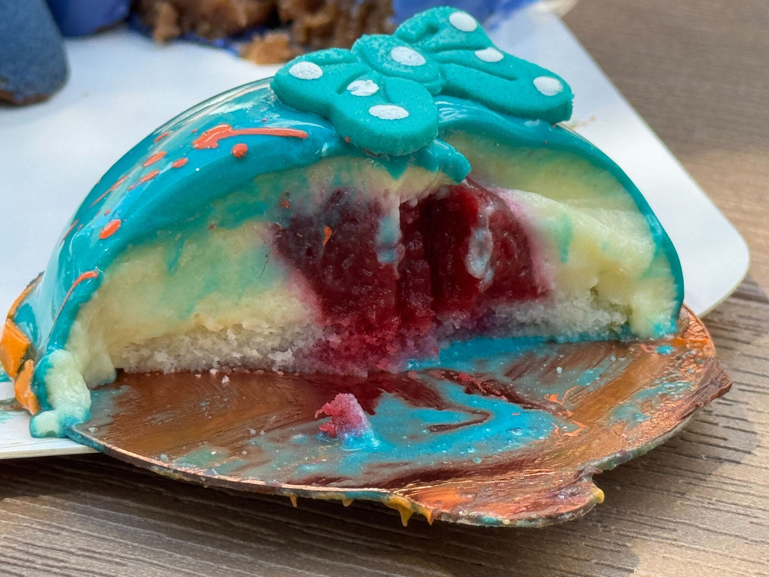 A blue and white mousse dessert at Disney Springs with a butterfly, revealing red fruit filling and cake base.