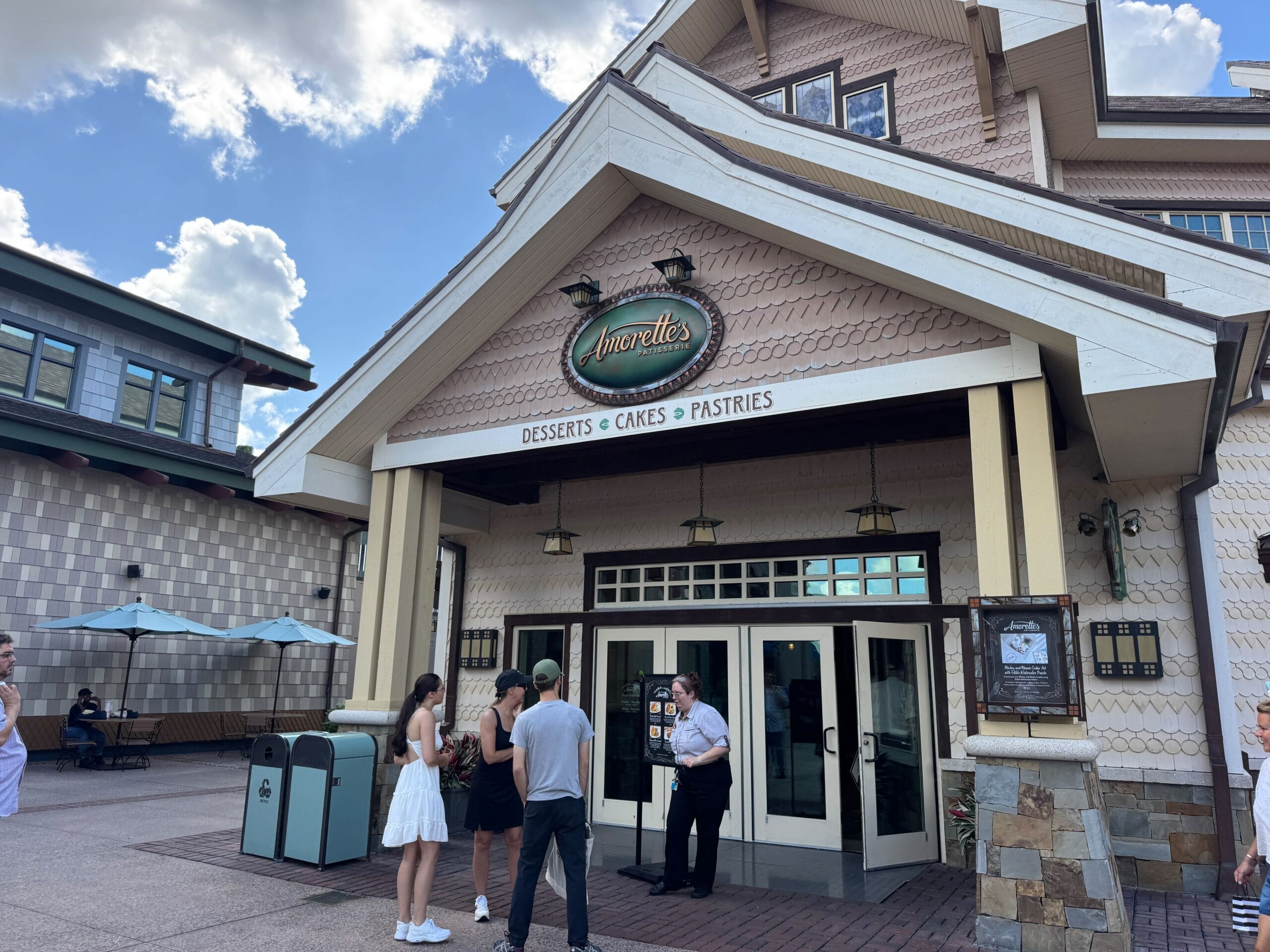 People gather outside Amorette's Patisserie at Disney Springs, seeking treats and great reviews under a partly cloudy sky.