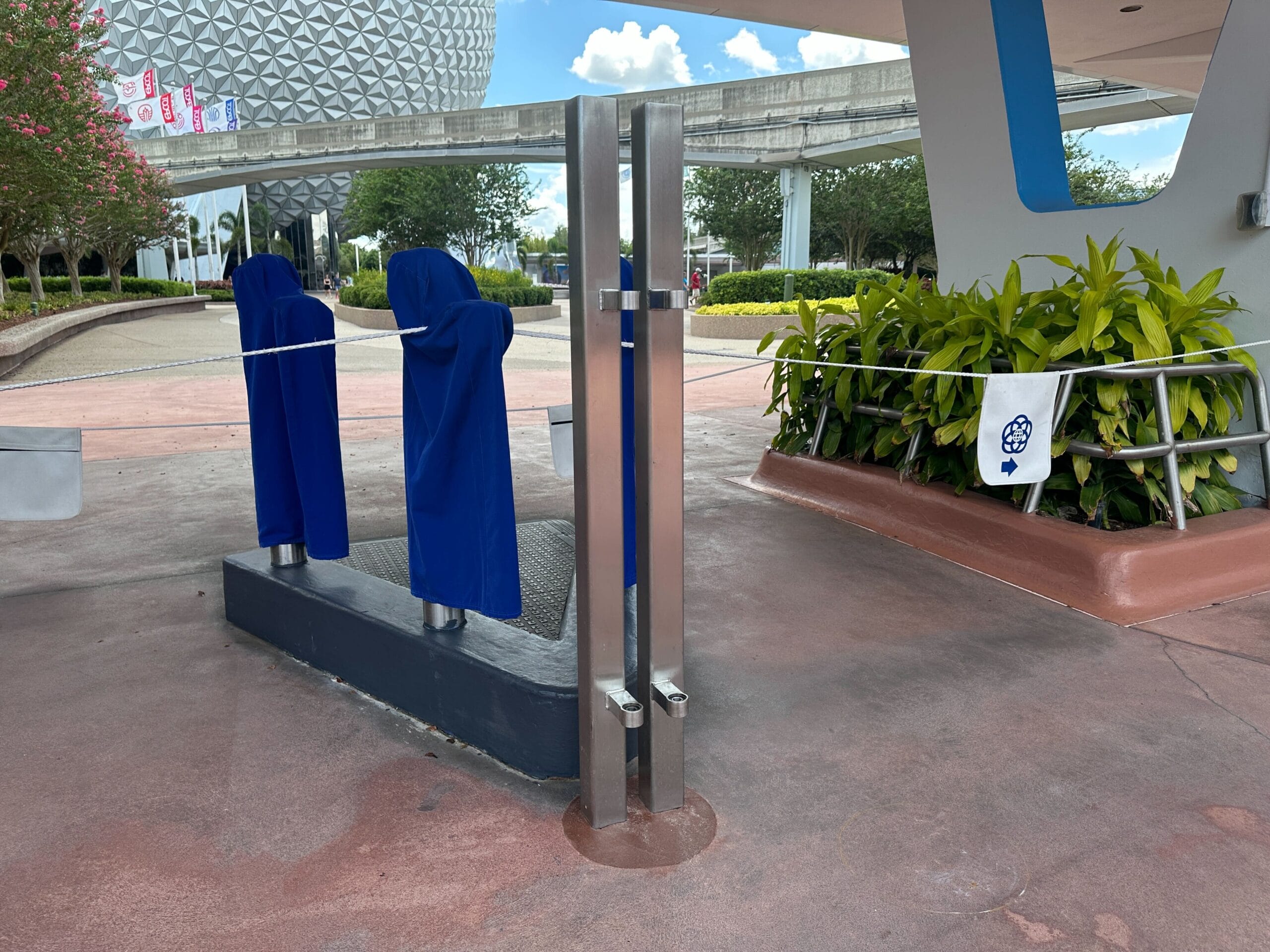 Two blue-covered devices and a metal pole stand near the Walt Disney World theme park entrance at Epcot.