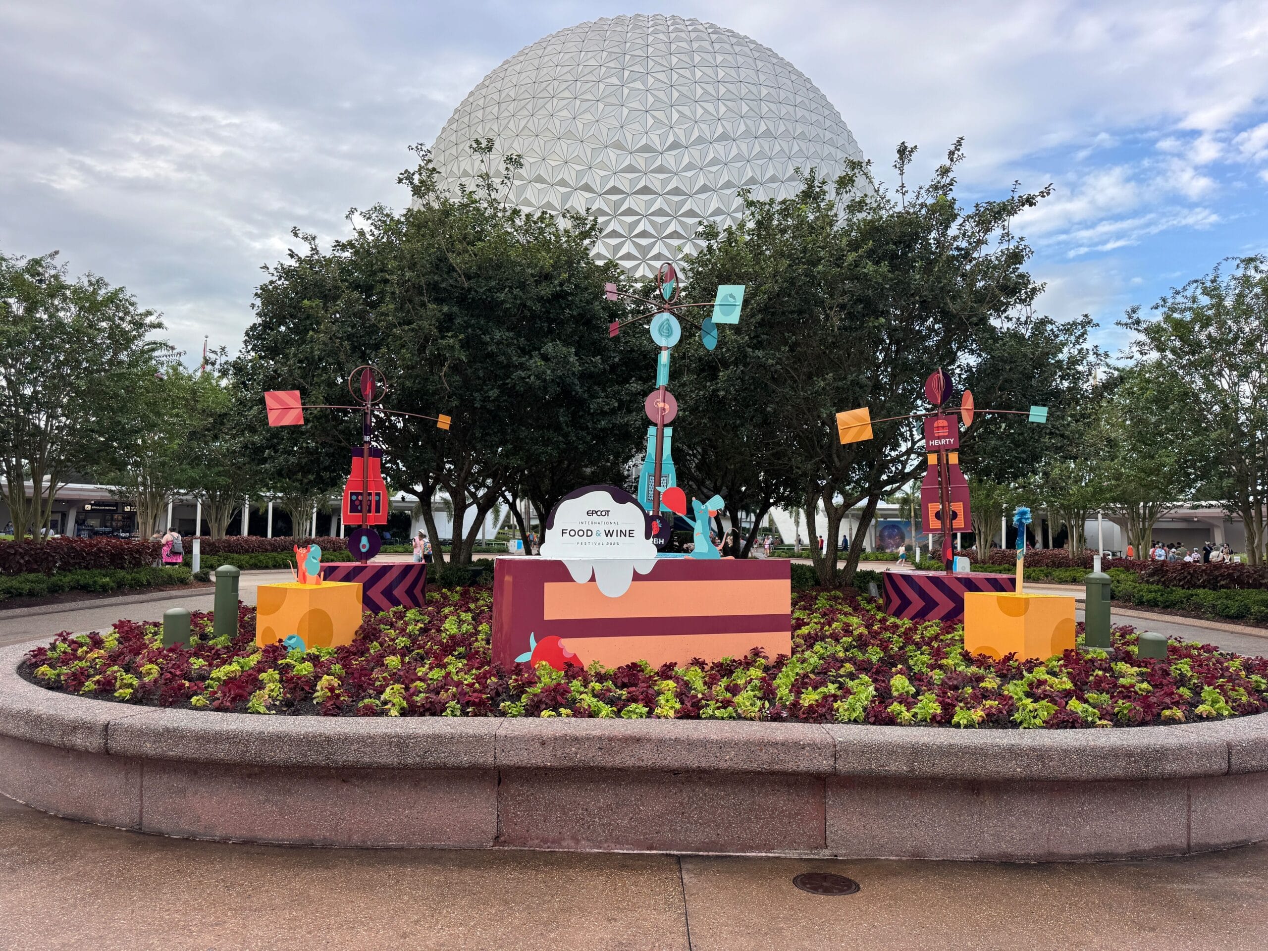 Vibrant EPCOT International Food & Wine Festival 2025 decorations bloom in front of the iconic geodesic dome.