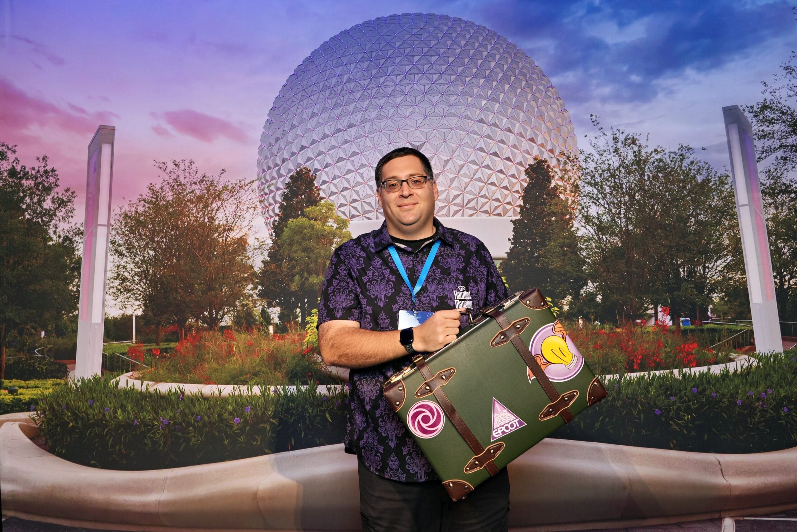 A man smiles with his suitcase in front of Epcot’s Spaceship Earth during the EPCOT Food & Wine Festival.