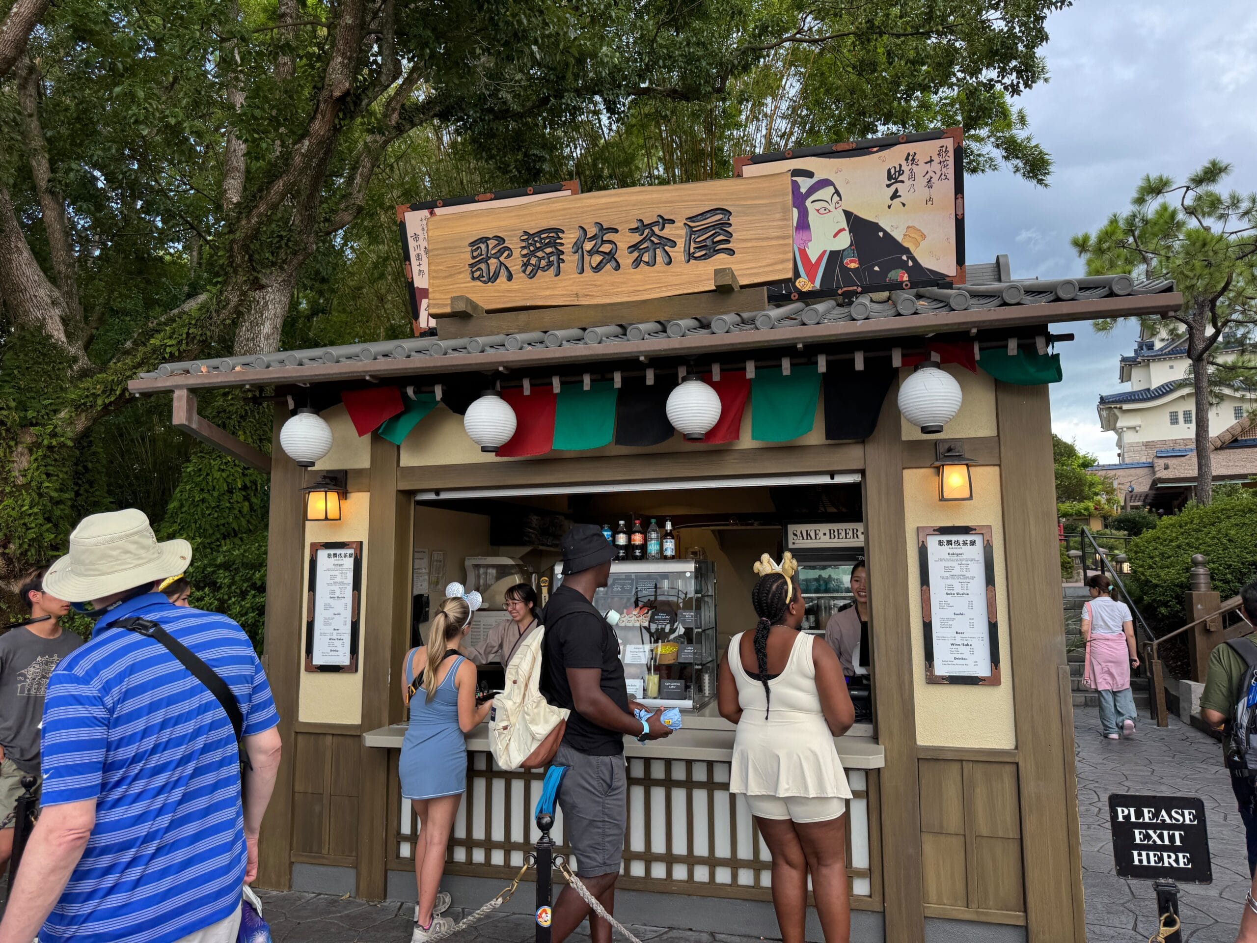 People stand in line at a Japanese tea kiosk, eager to try the New Kakigori under lanterns and a traditional sign.