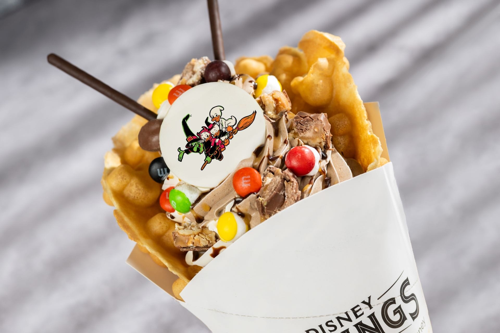 Bubble waffle cone filled with chocolate soft serve, candies, and a Walt Disney World cartoon topper—perfect 2025 Halloween treat!