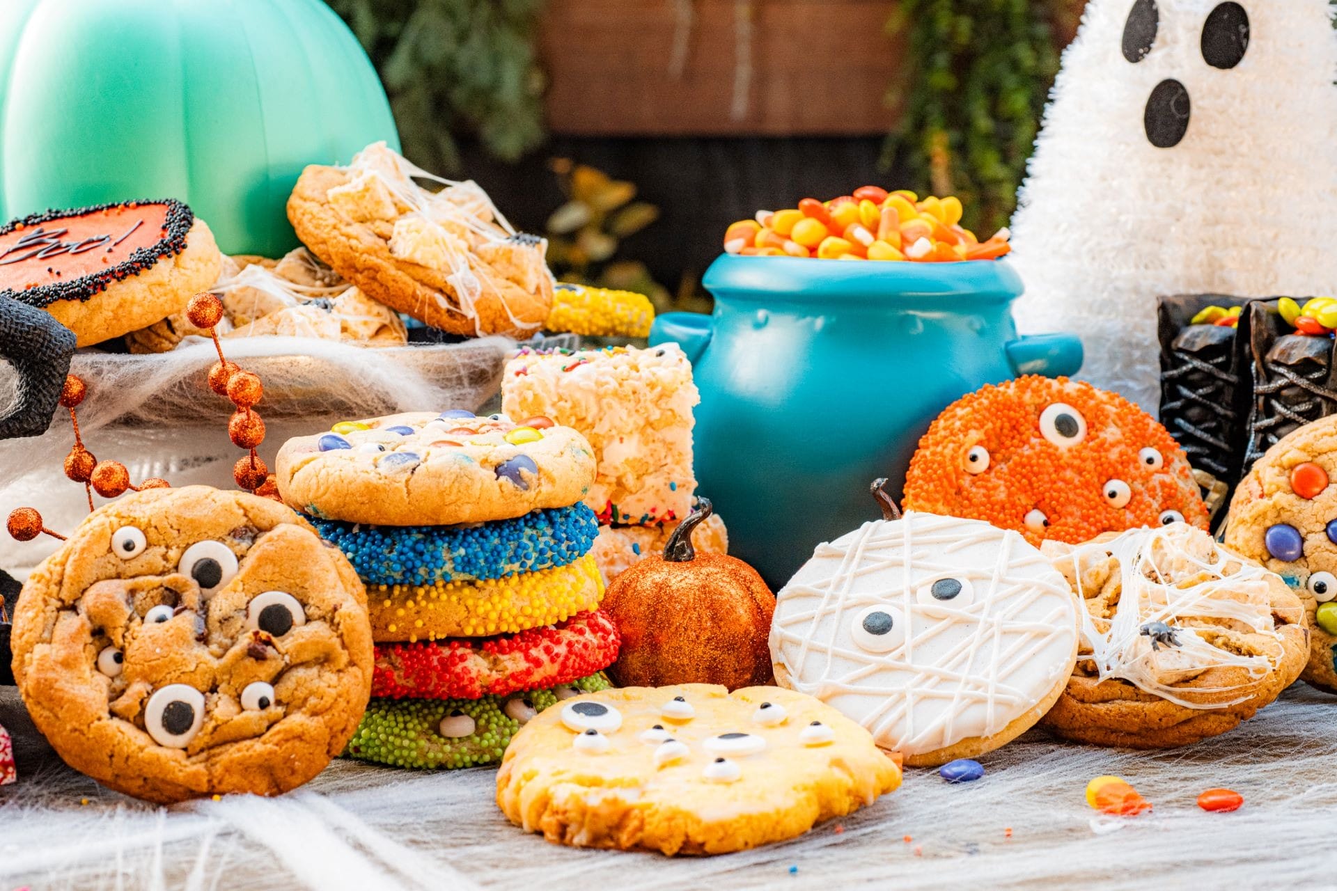 Assorted 2025 Halloween Treats cookies with candy eyes and sprinkles on a festive table with decorations.