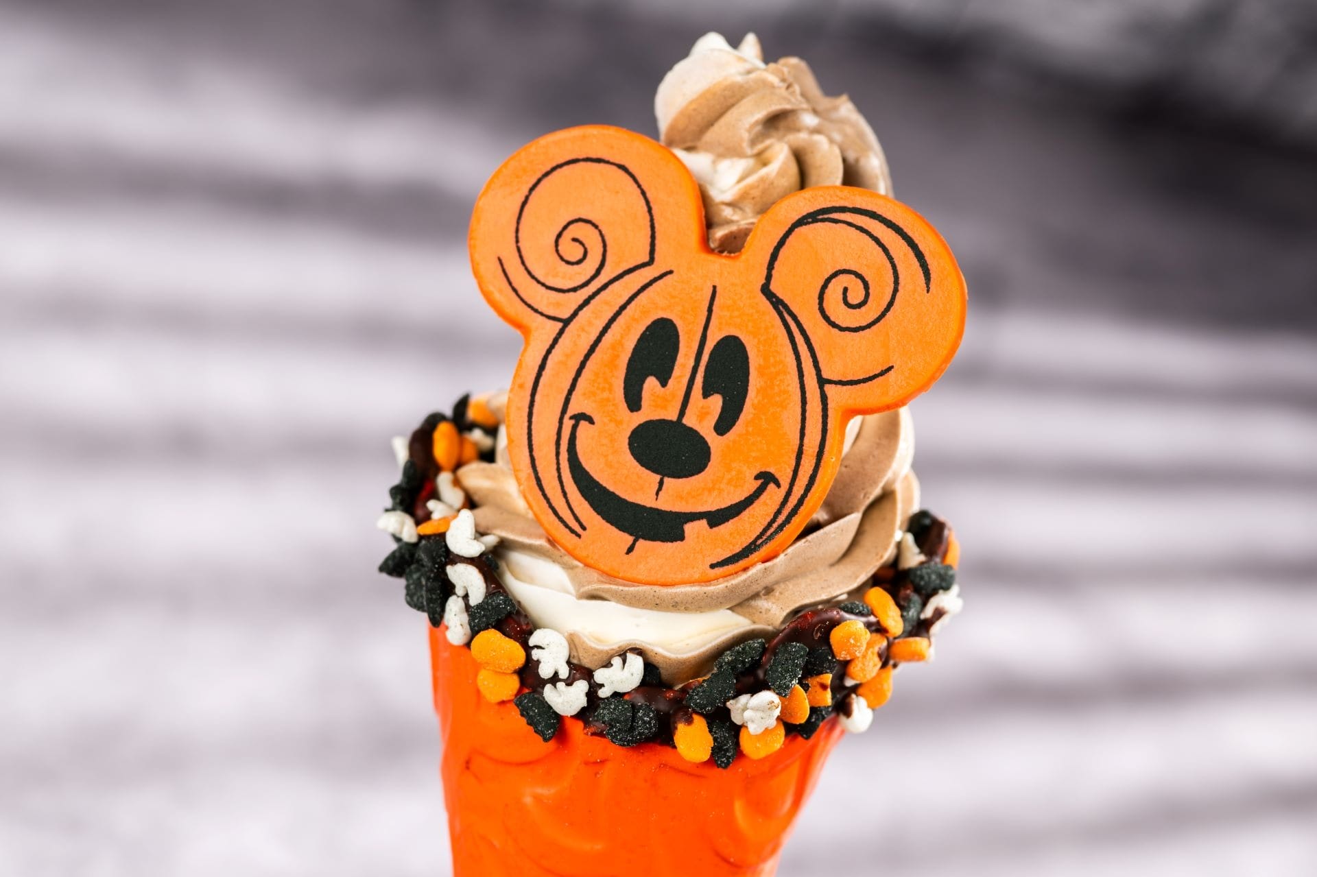 A 2025 Halloween Treat at Walt Disney World: ice cream cone with chocolate swirl, orange decor, and a cartoon mouse cookie.