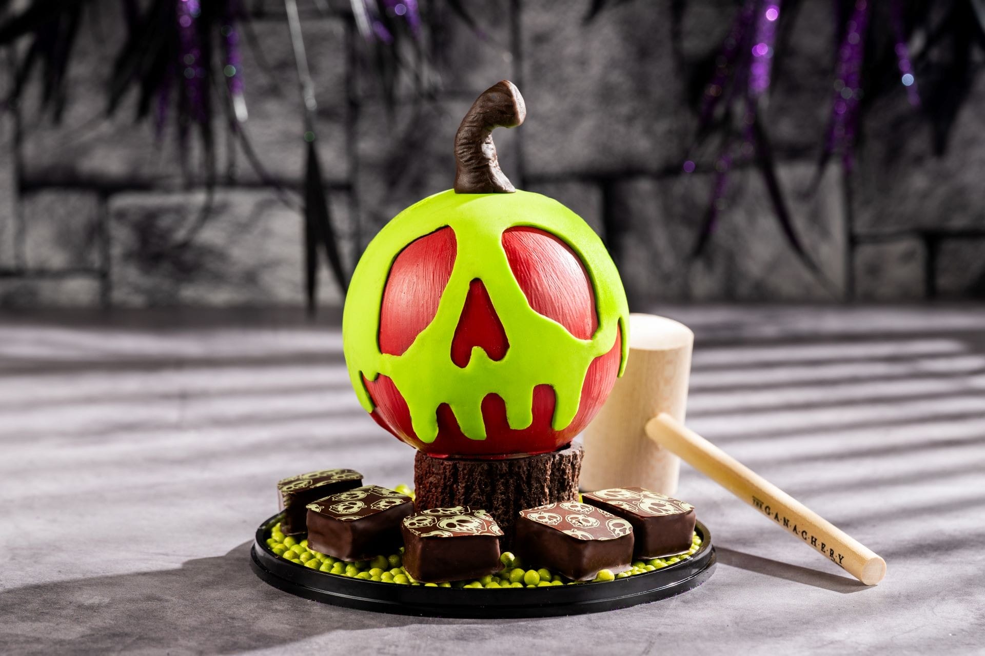 A green and red candy apple shaped like a poisoned skull, part of the 2025 Halloween Treats at Walt Disney World.