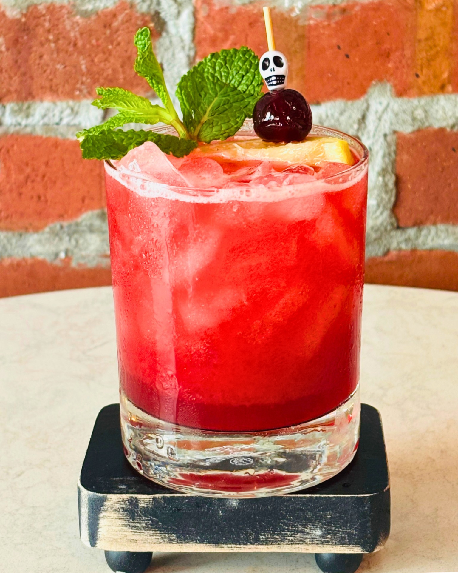 A red cocktail with ice, mint, and a cherry on a skull pick—one of 2025 Halloween treats at Walt Disney World.