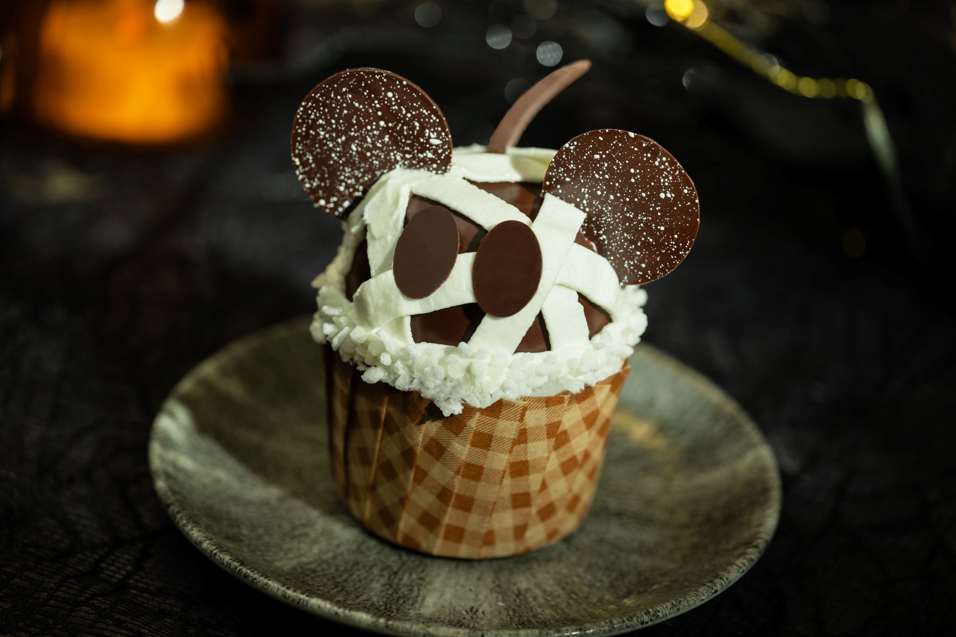 A 2025 Halloween Treat, this cupcake mummy with chocolate ears and eyes sits on a ceramic plate at Walt Disney World.