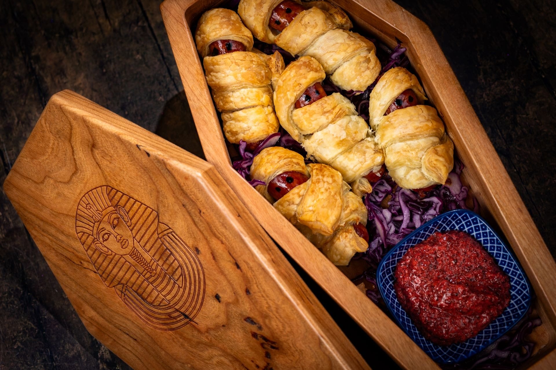 Puff pastry-wrapped sausage mummies in a wooden coffin box—one of 2025 Halloween Treats at Walt Disney World.