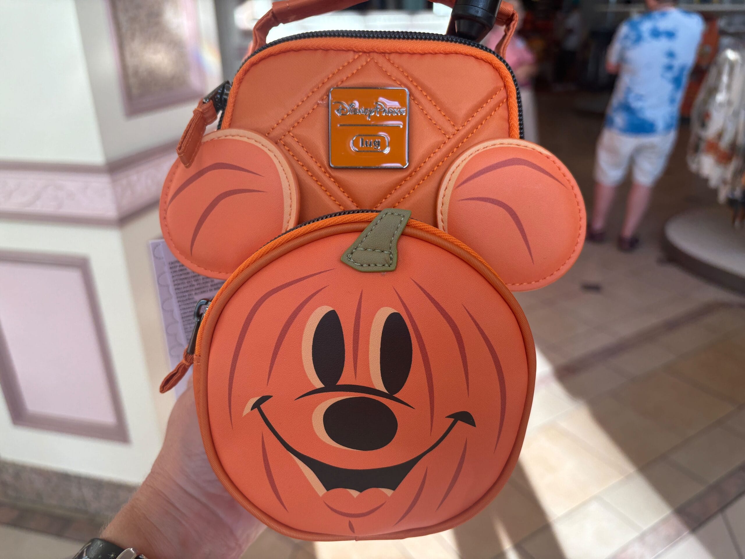 Hand holding an orange Mickey Mouse pumpkin-shaped bag, browsing Halloween merchandise at Walt Disney World.