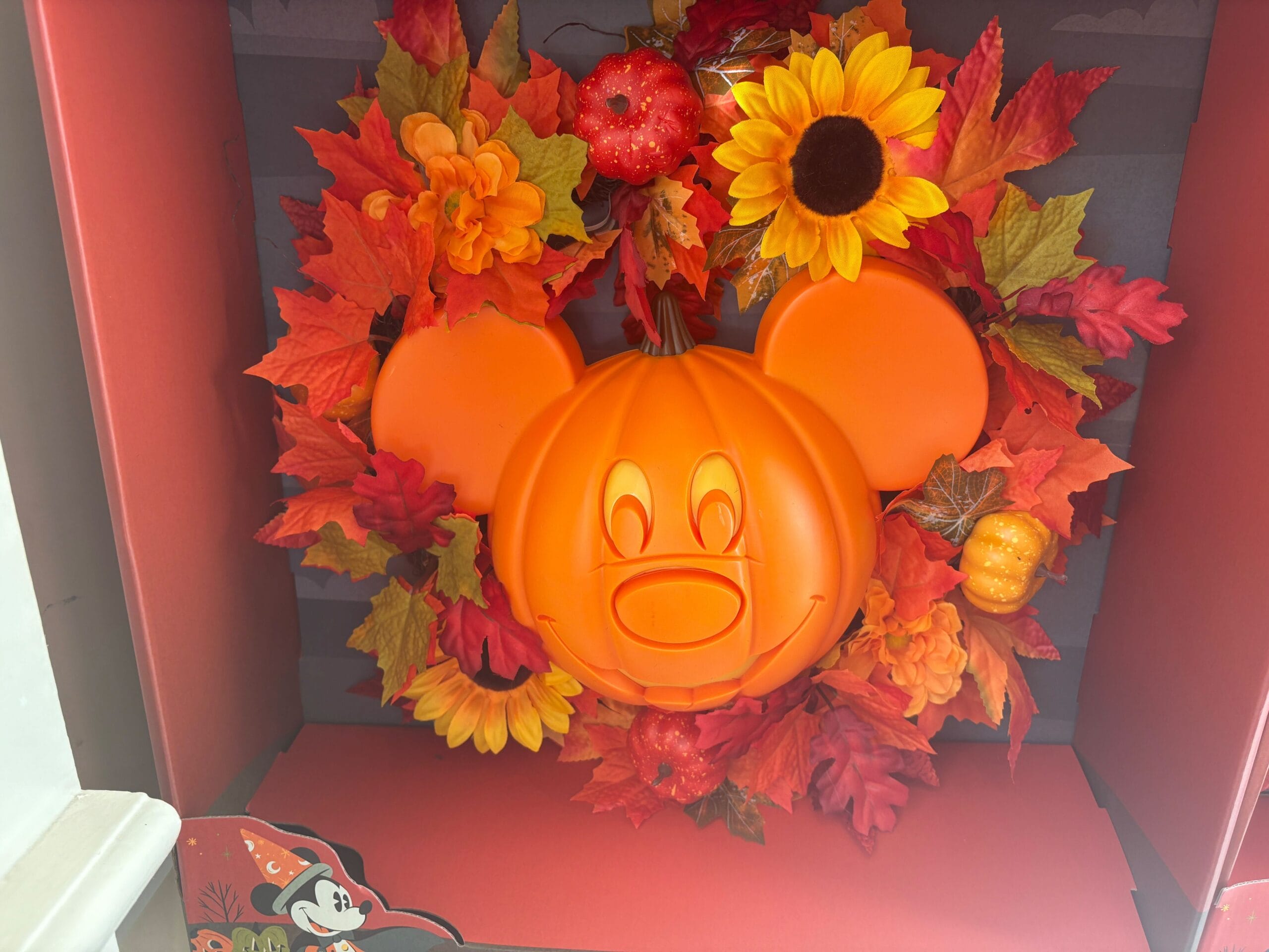 A Mickey Mouse pumpkin surrounded by festive fall decorations inspired by Walt Disney World Halloween merchandise.