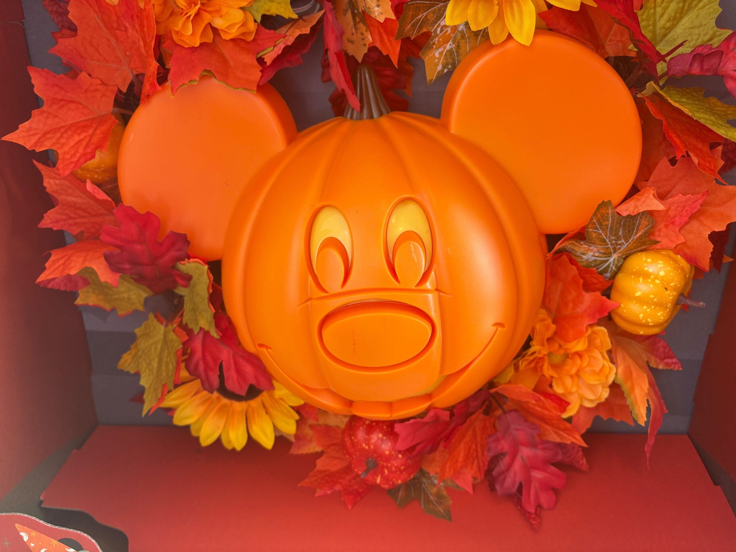 An orange Mickey Mouse pumpkin surrounded by autumn leaves—a festive Walt Disney World Halloween merchandise piece.