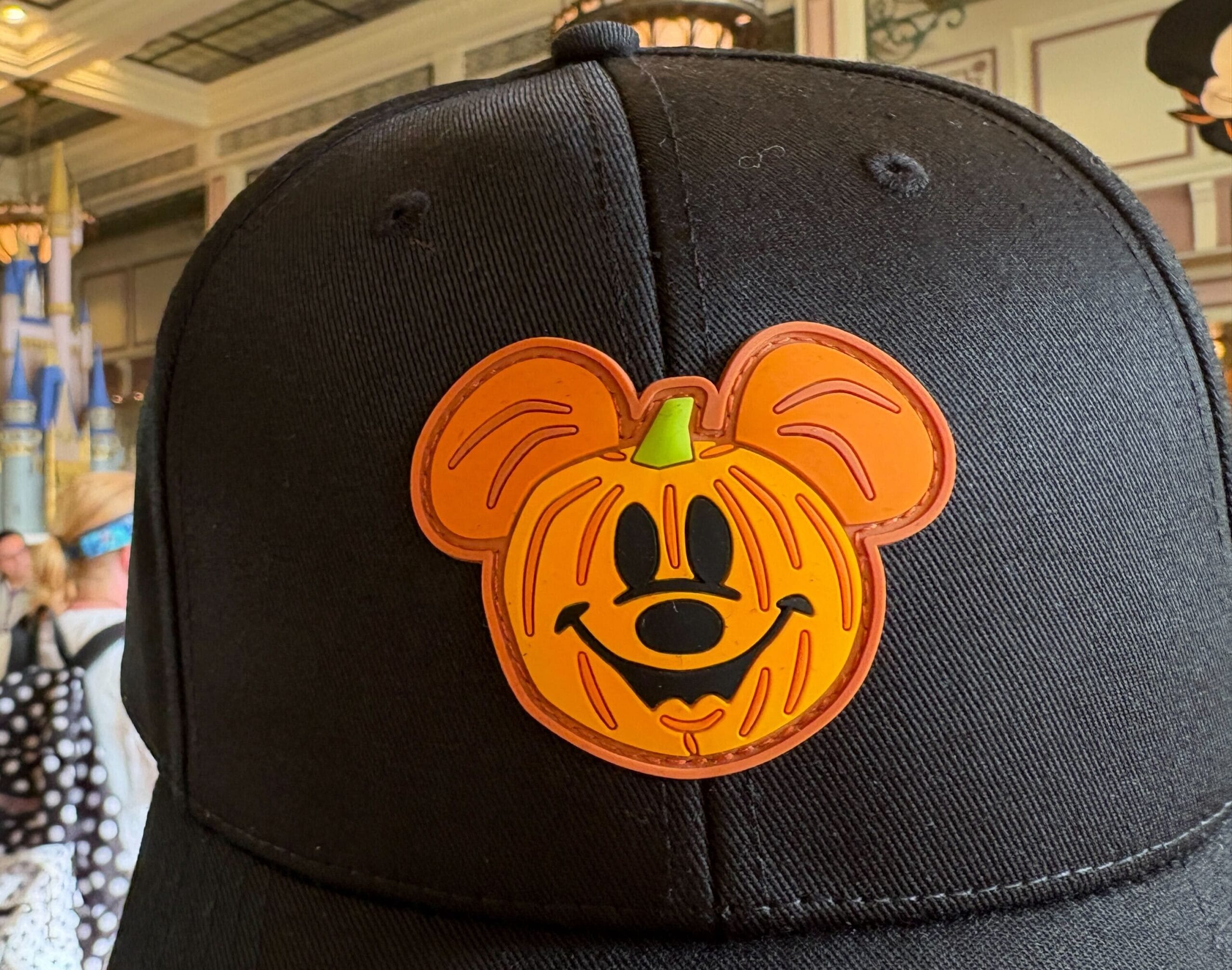 Black hat with an orange pumpkin Mickey Mouse patch, part of Walt Disney World Halloween merchandise.