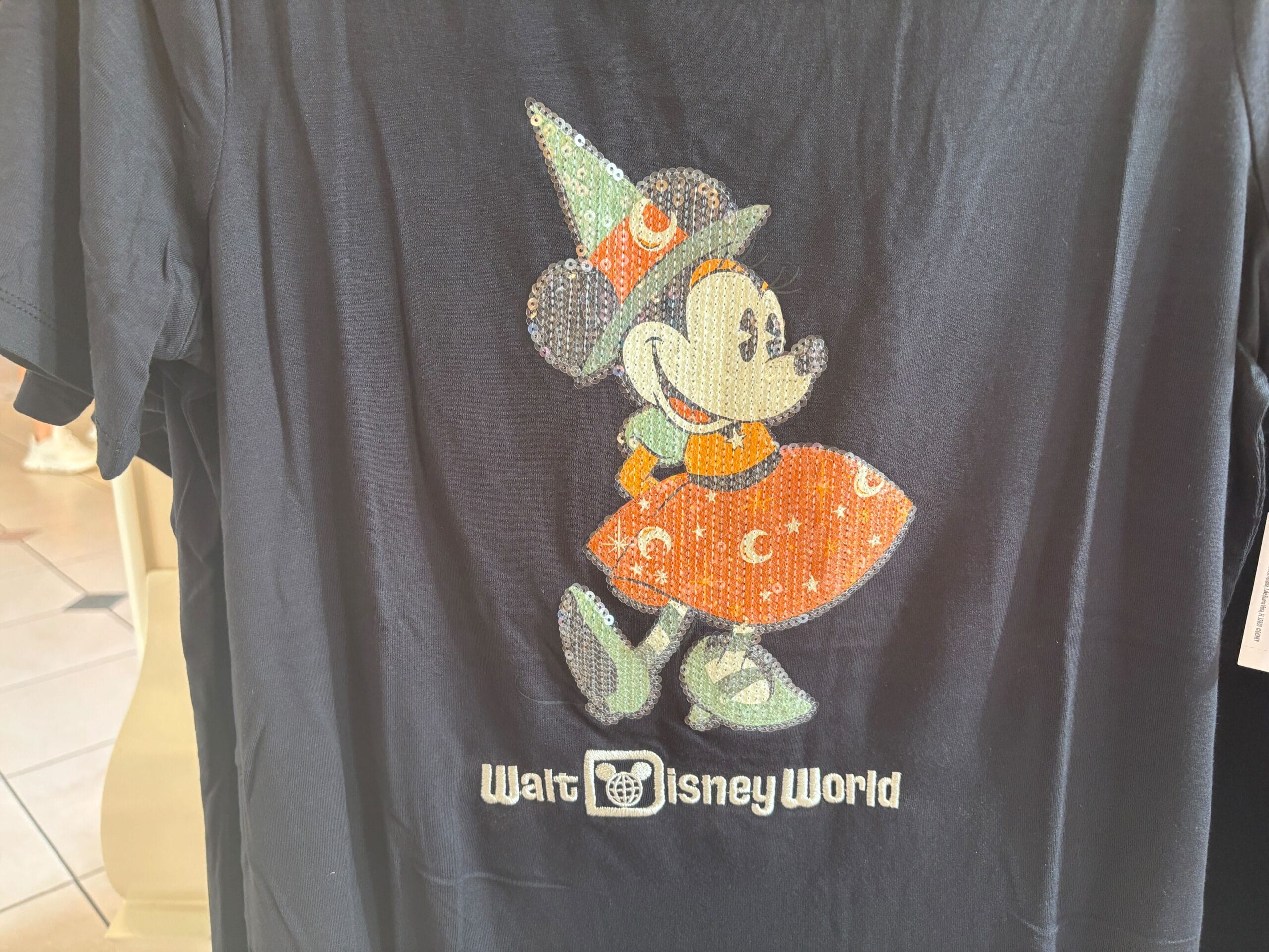 Black T-shirt with a sequined Minnie Mouse in a Halloween witch costume—exclusive Halloween merchandise at Walt Disney World.