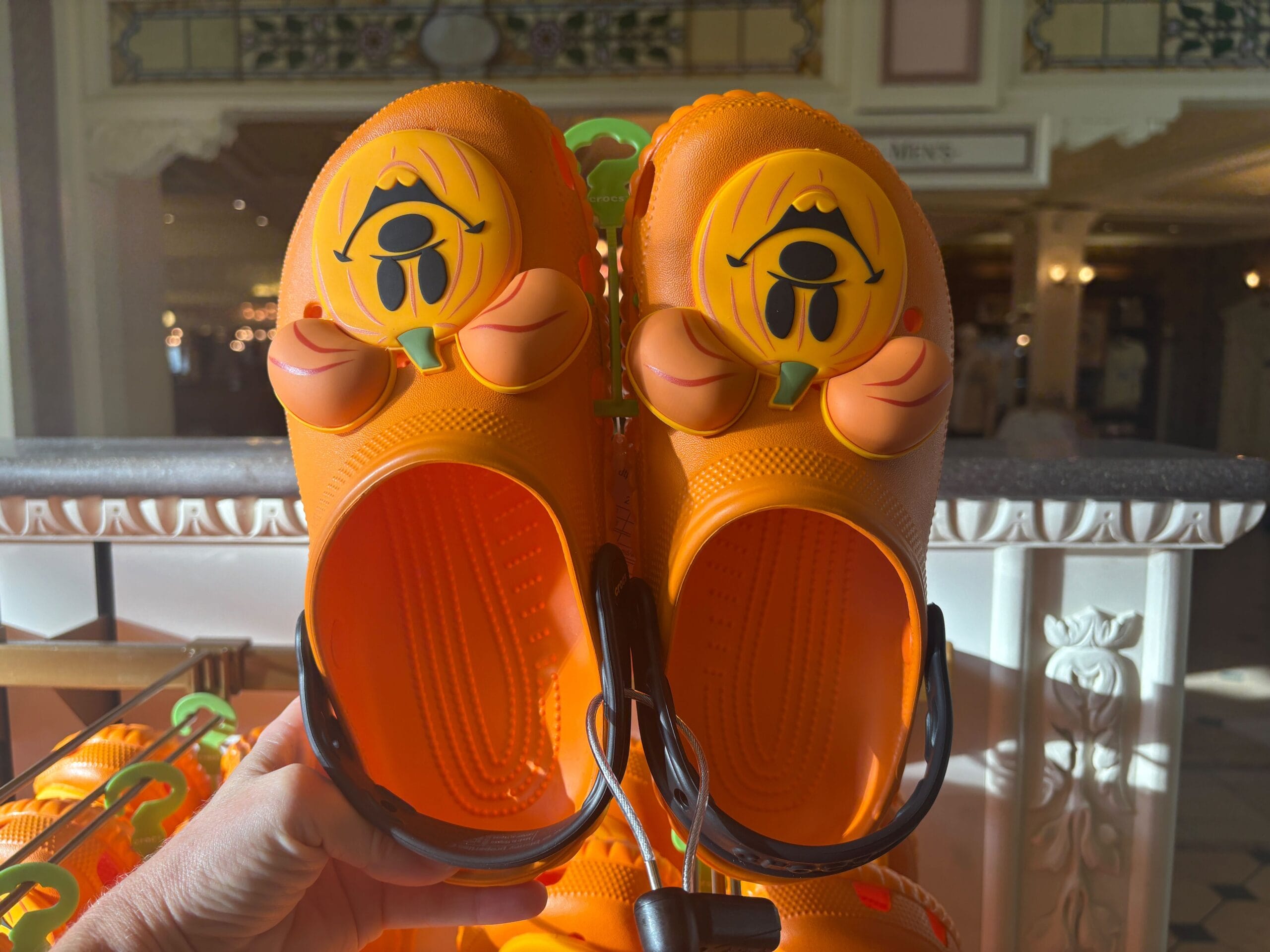 Orange clogs with a cartoon character face and floppy ears feature among Halloween merchandise in a well-lit store.