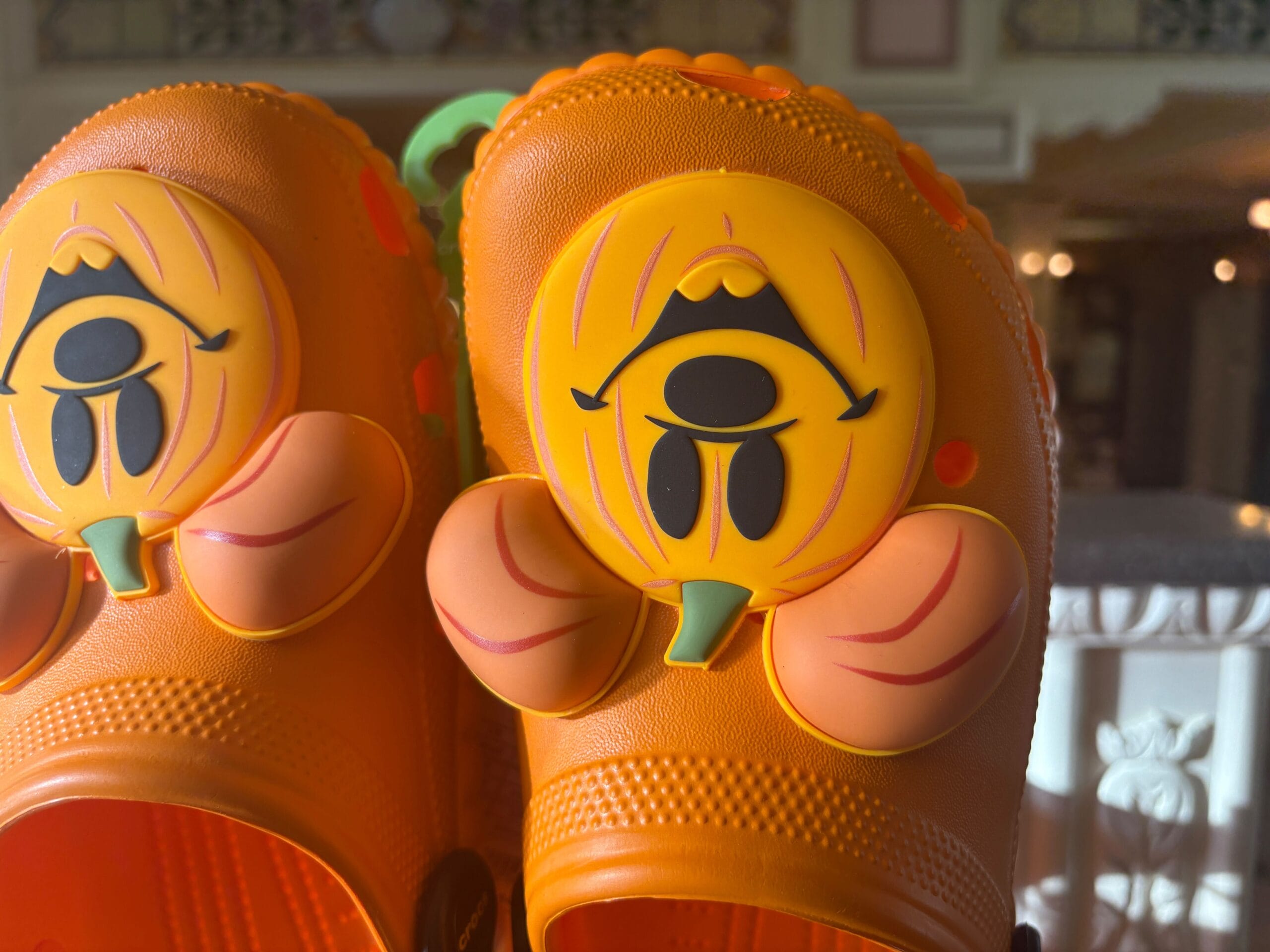 Close-up of orange clogs with pumpkin face decorations, part of fun Halloween merchandise at Walt Disney World.