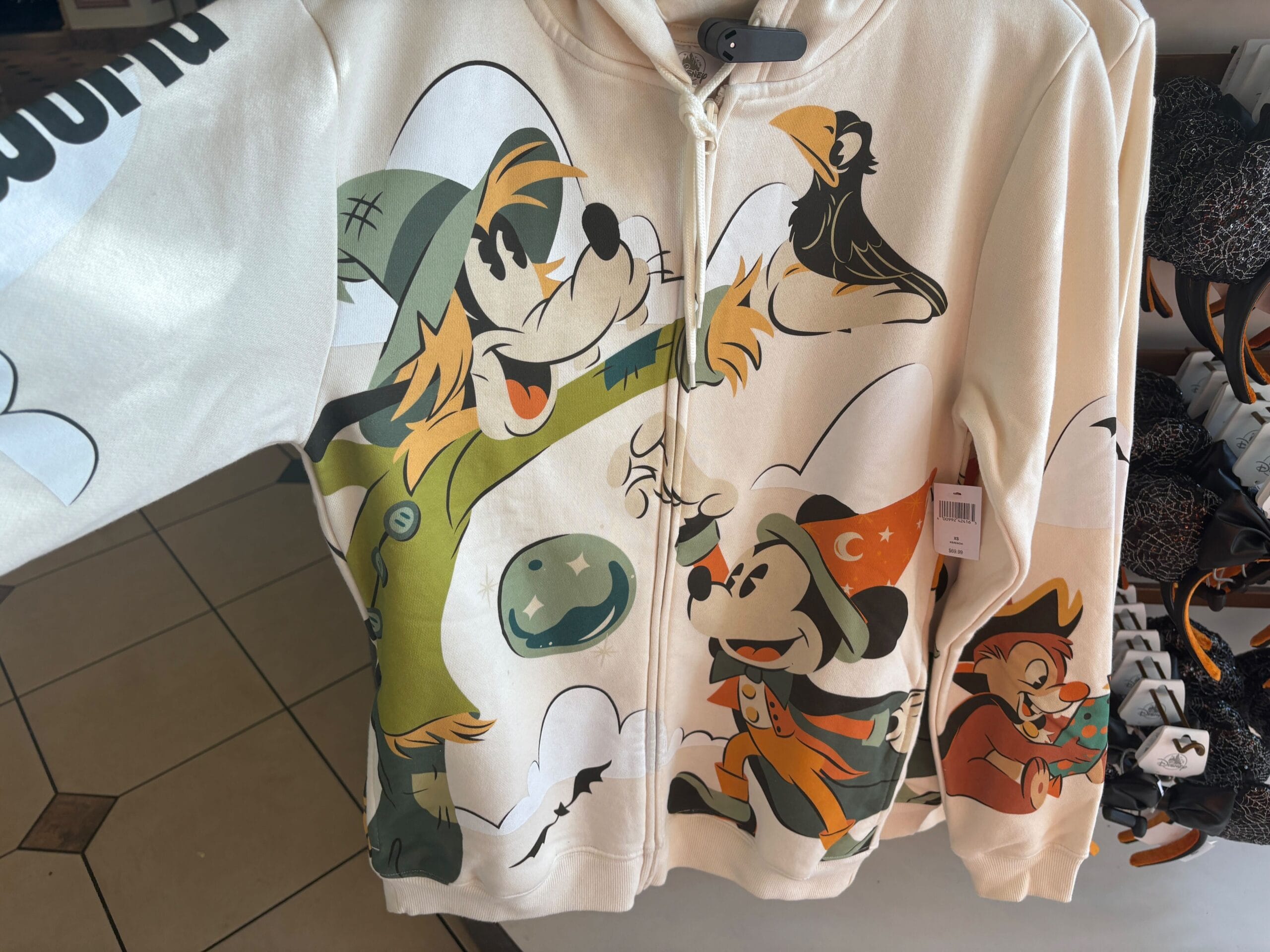 Beige hoodie featuring cartoon characters in Halloween costumes—fun Walt Disney World Halloween merchandise.
