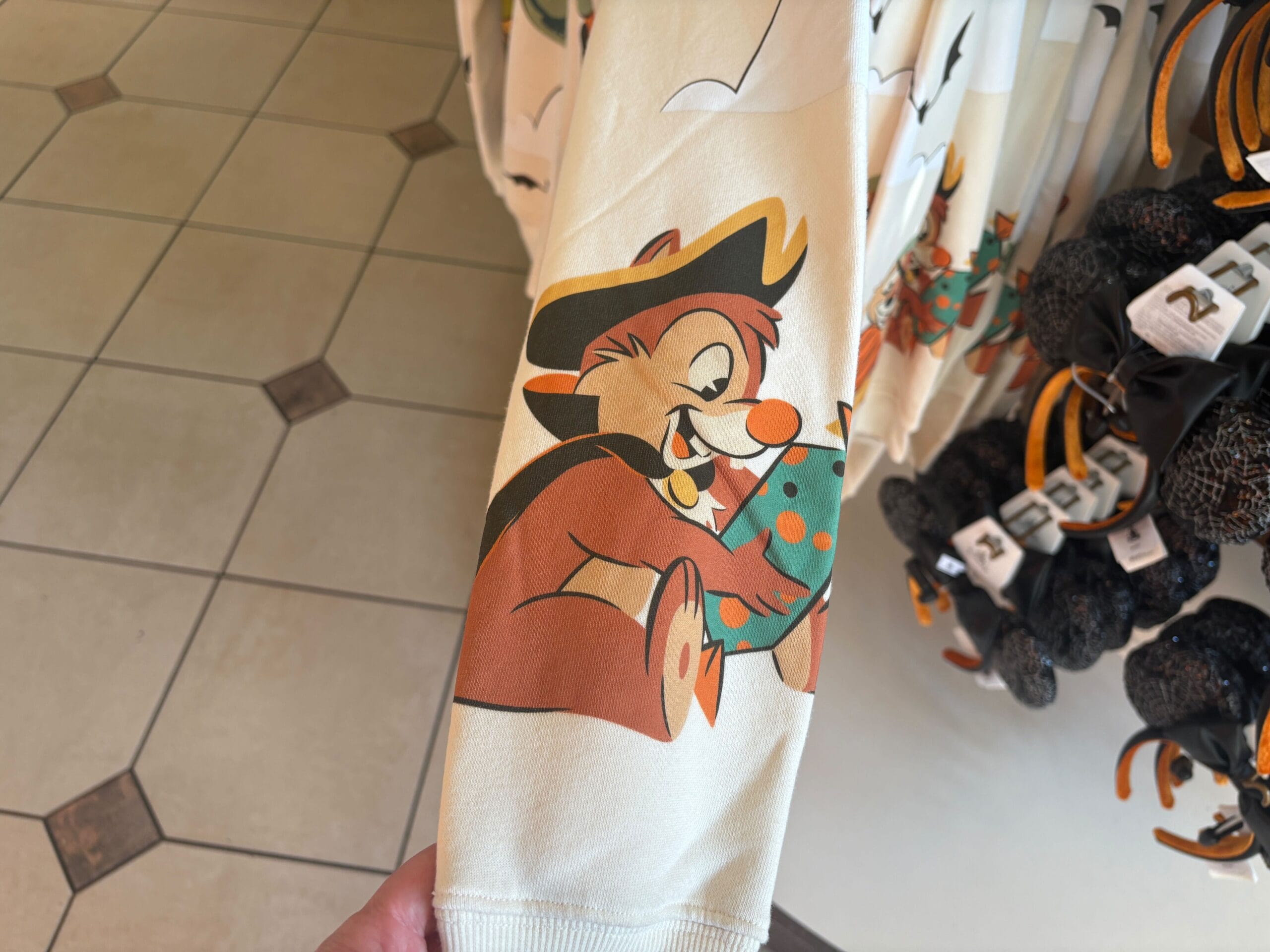 A shirt sleeve with a cartoon animal in a hat holding a spotted egg, part of Halloween merchandise at Walt Disney World.