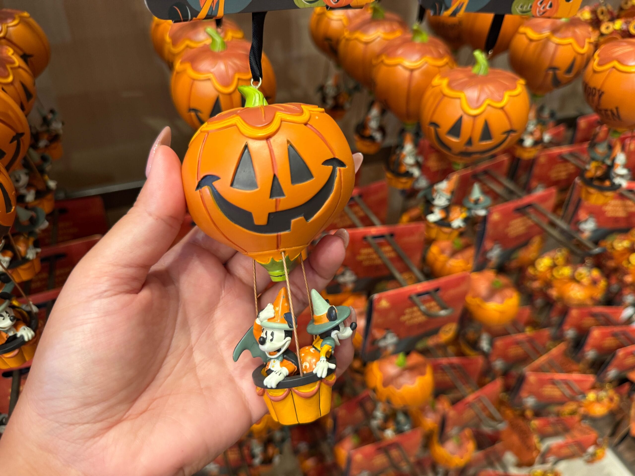 Hand holding 2025 Halloween Merchandise: a jack-o’-lantern hot air balloon with cartoon mice at Walt Disney World.